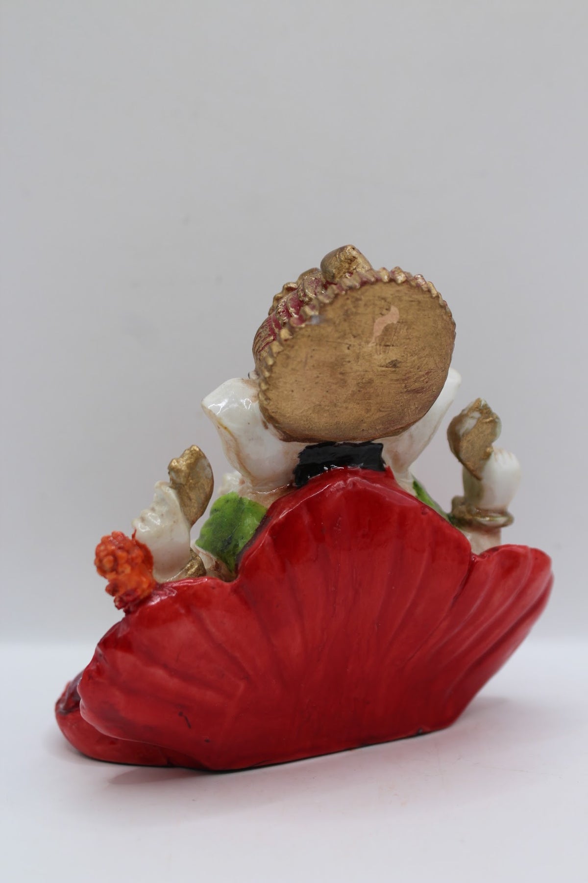 Resin Ganesh murti on red leaf, orange dhoti, back view