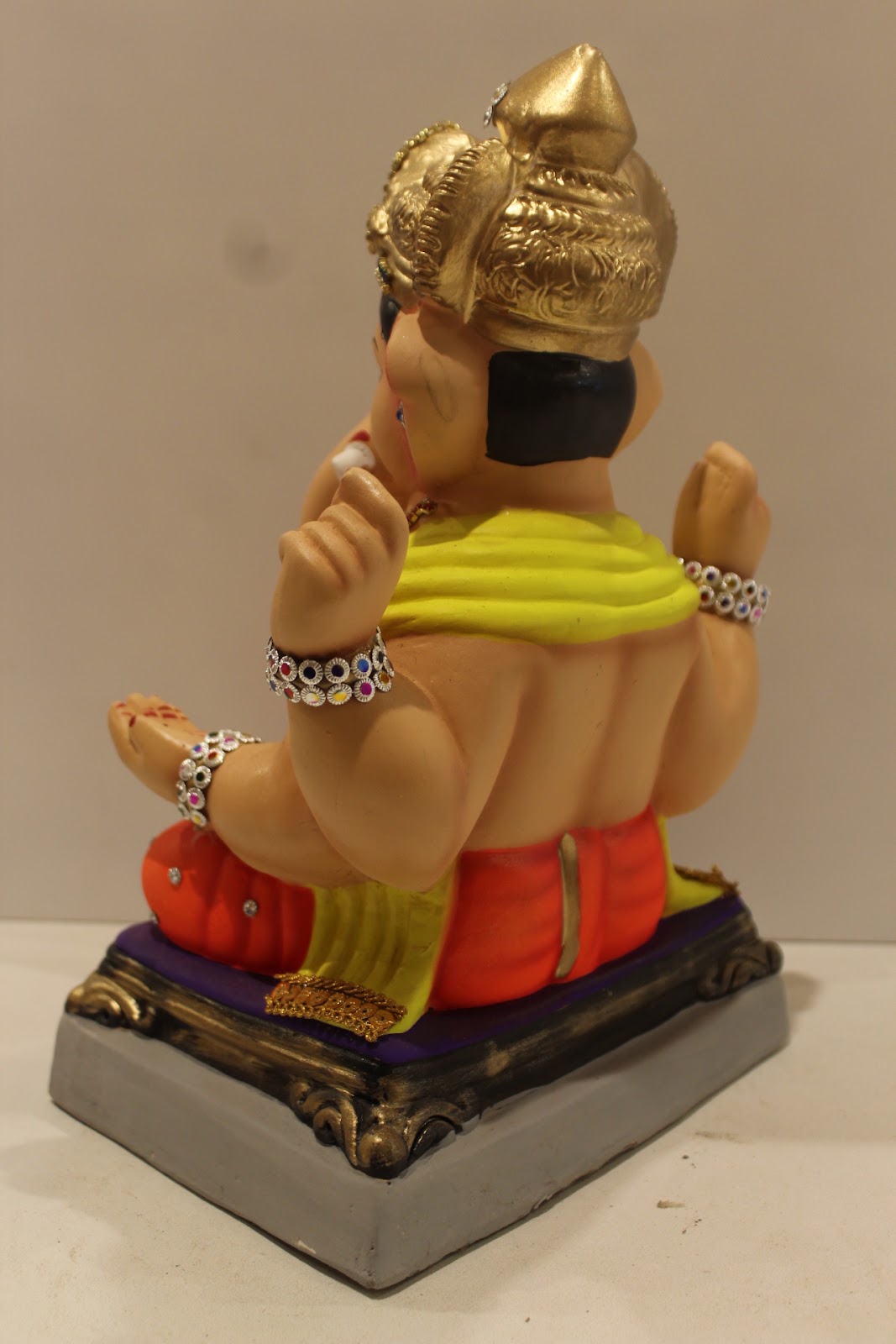 Eco-friendly clay Ganesh idol in jewellery style with yellow khes and orange dhoti, back view