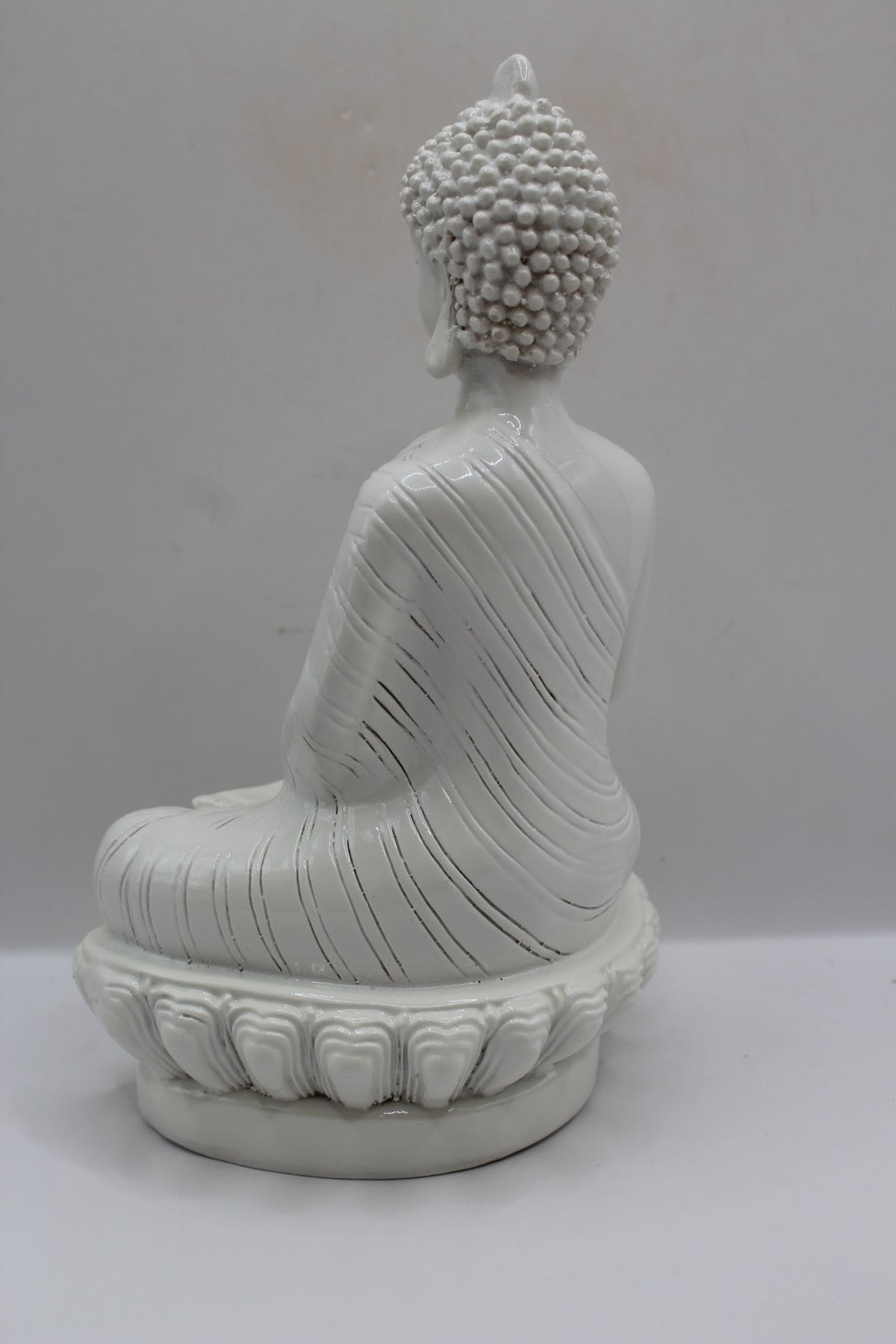 White resin Buddha statue meditating on a lotus base, back view