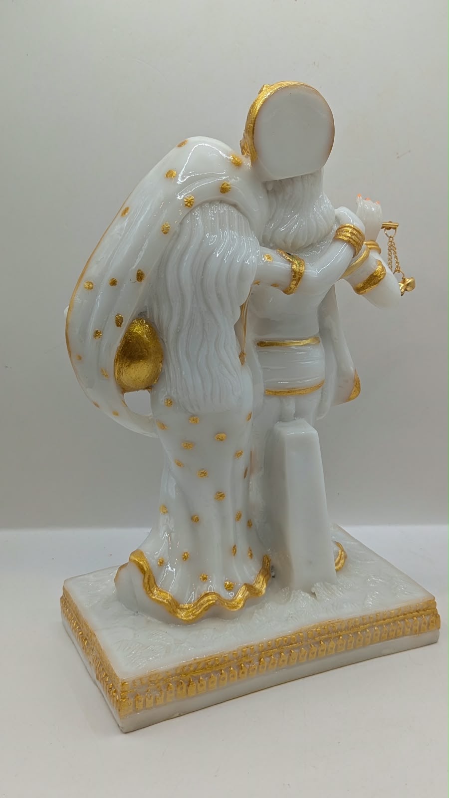 White and gold Radha Krishna statue with flute, back view