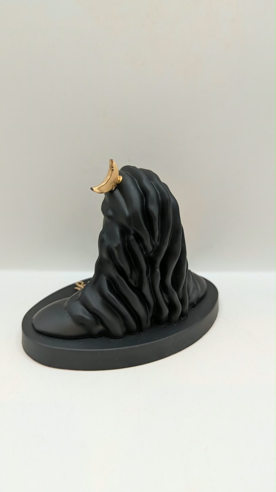 Black Adiyogi Shiva statue with gold trishul, back view
