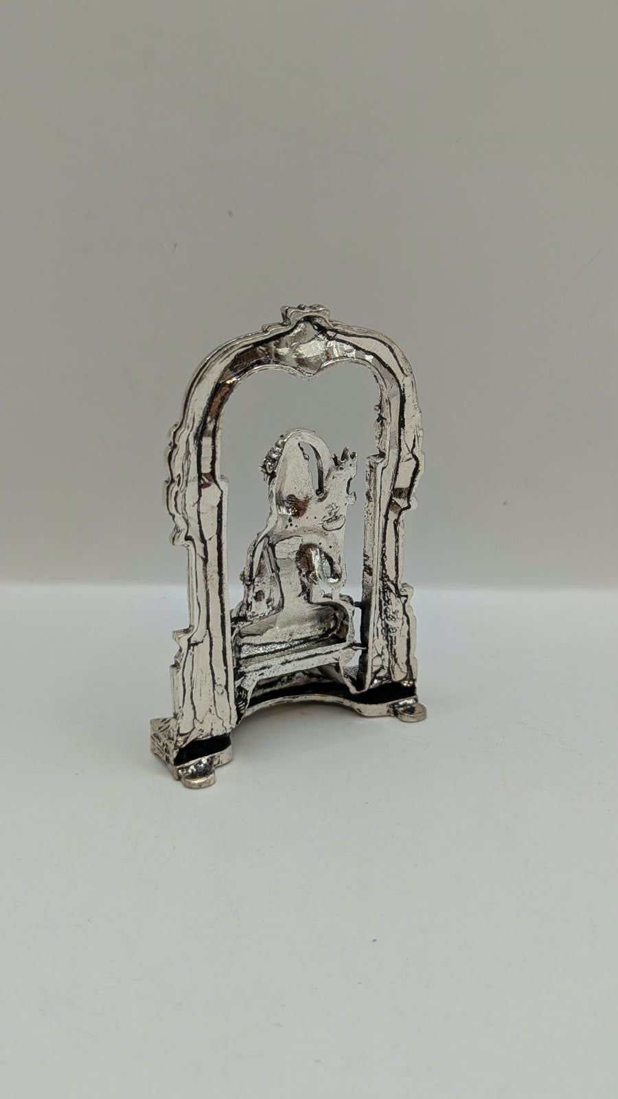 Silver sitting Shiva murti in temple arch, back view