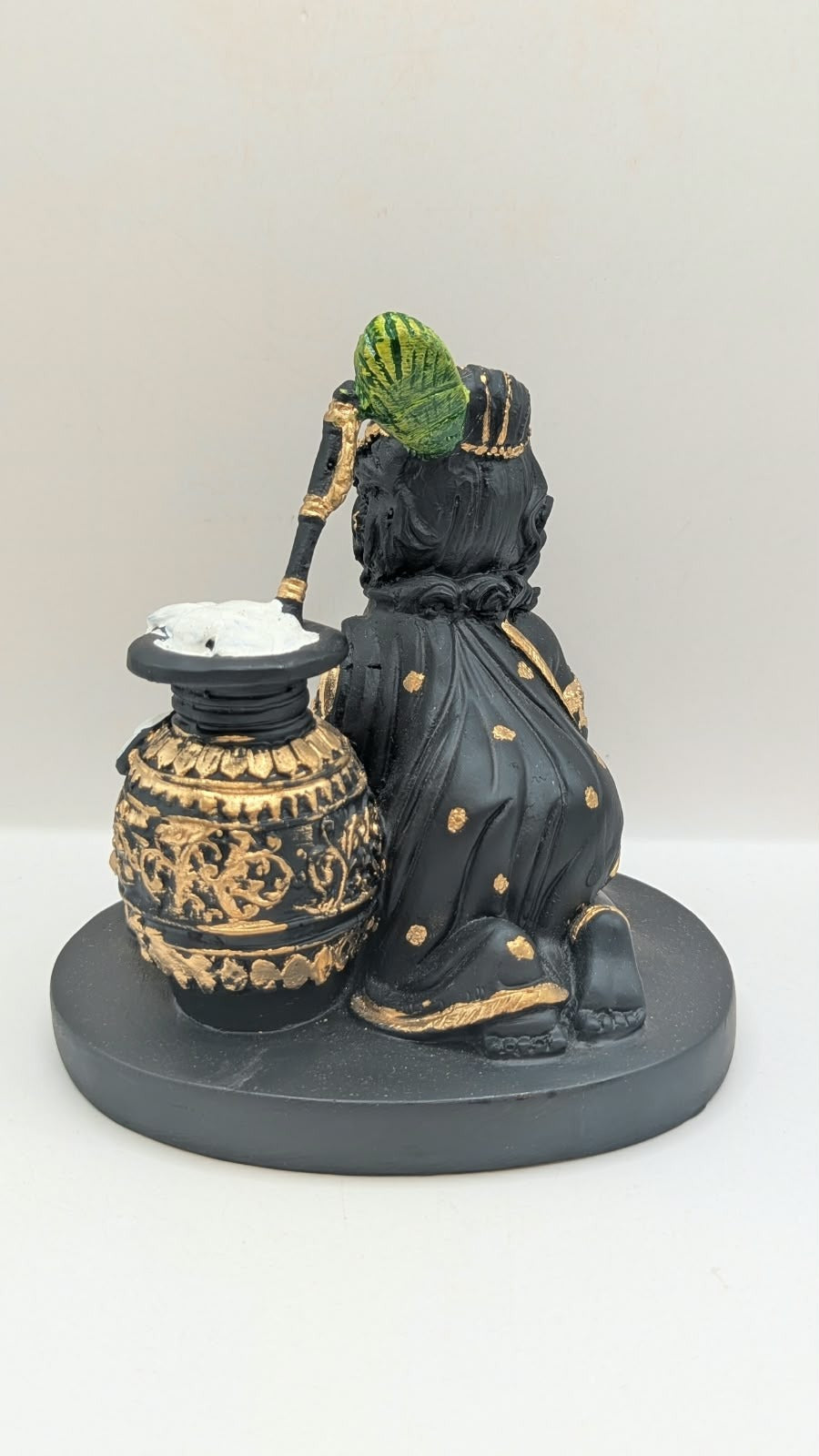 Black and gold baby Krishna statue with butter pot, back view