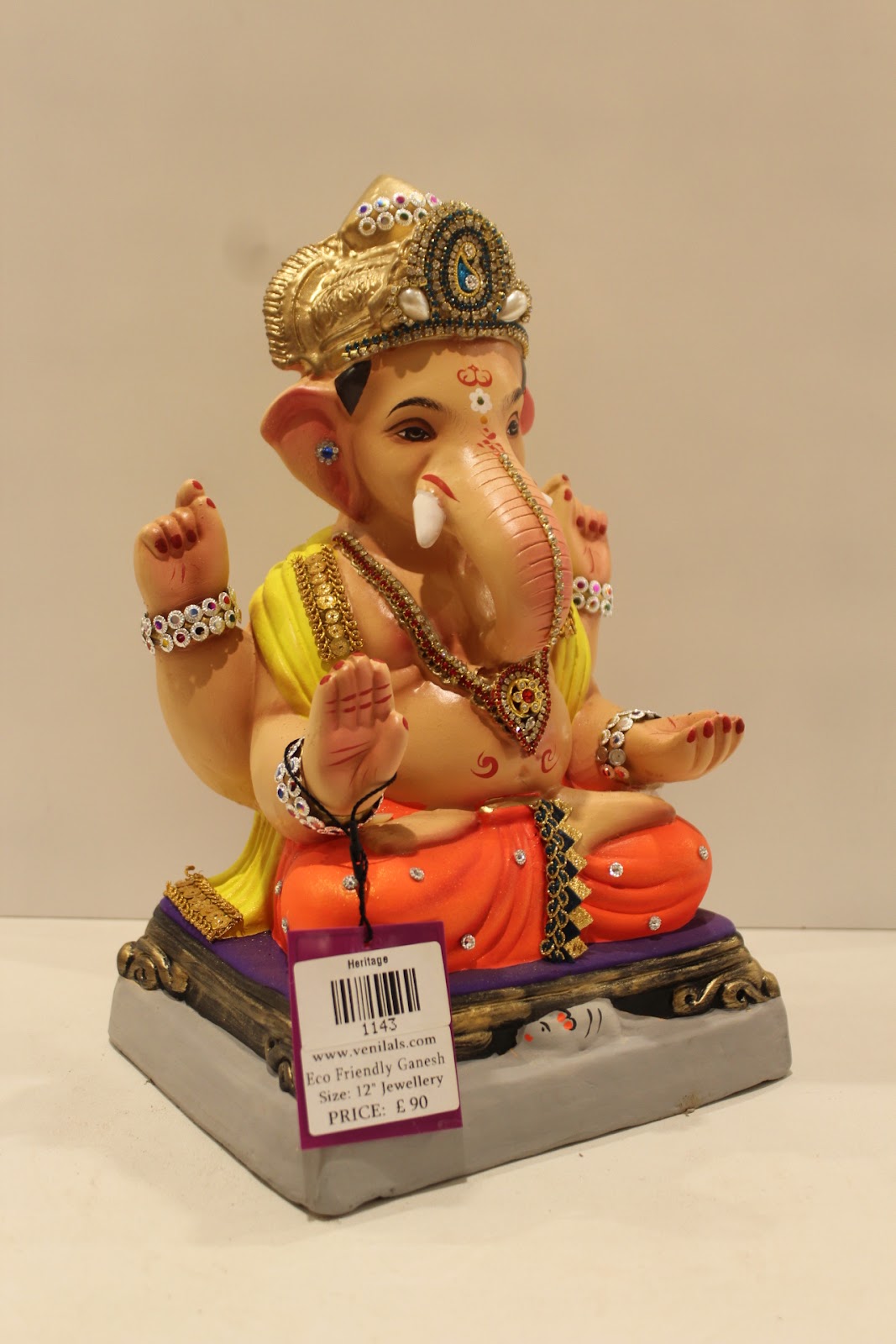 Eco-friendly clay Ganesh idol in jewellery style with yellow khes and orange dhoti, side view