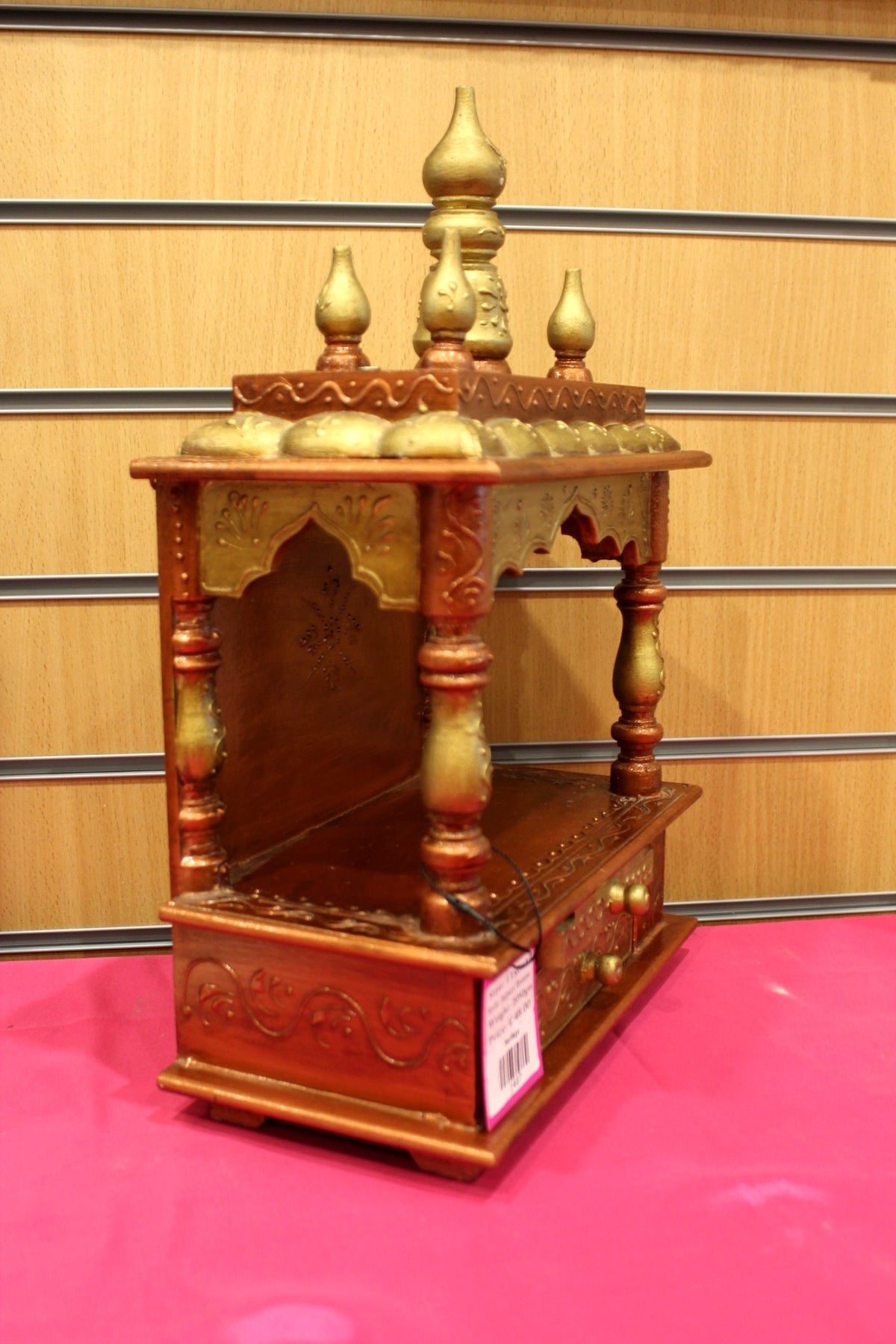 Small carved wooden mandir shown at a side angle