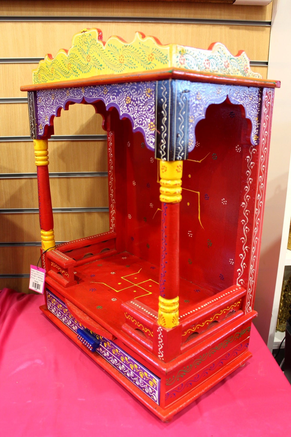 Red and yellow painted mandir shown at a side angle