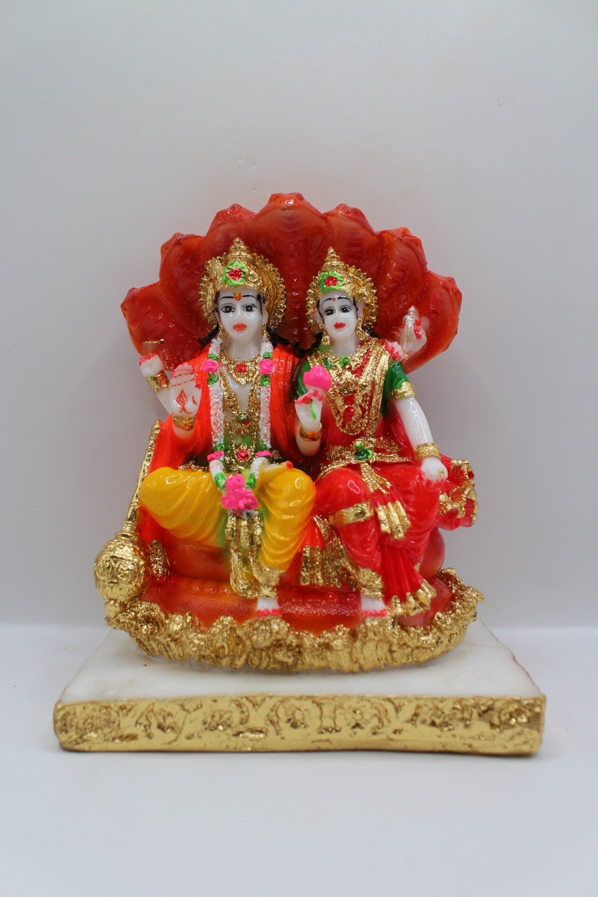 Red resin Vishnu Laxmi murti, seated under Sheshnaag, front view