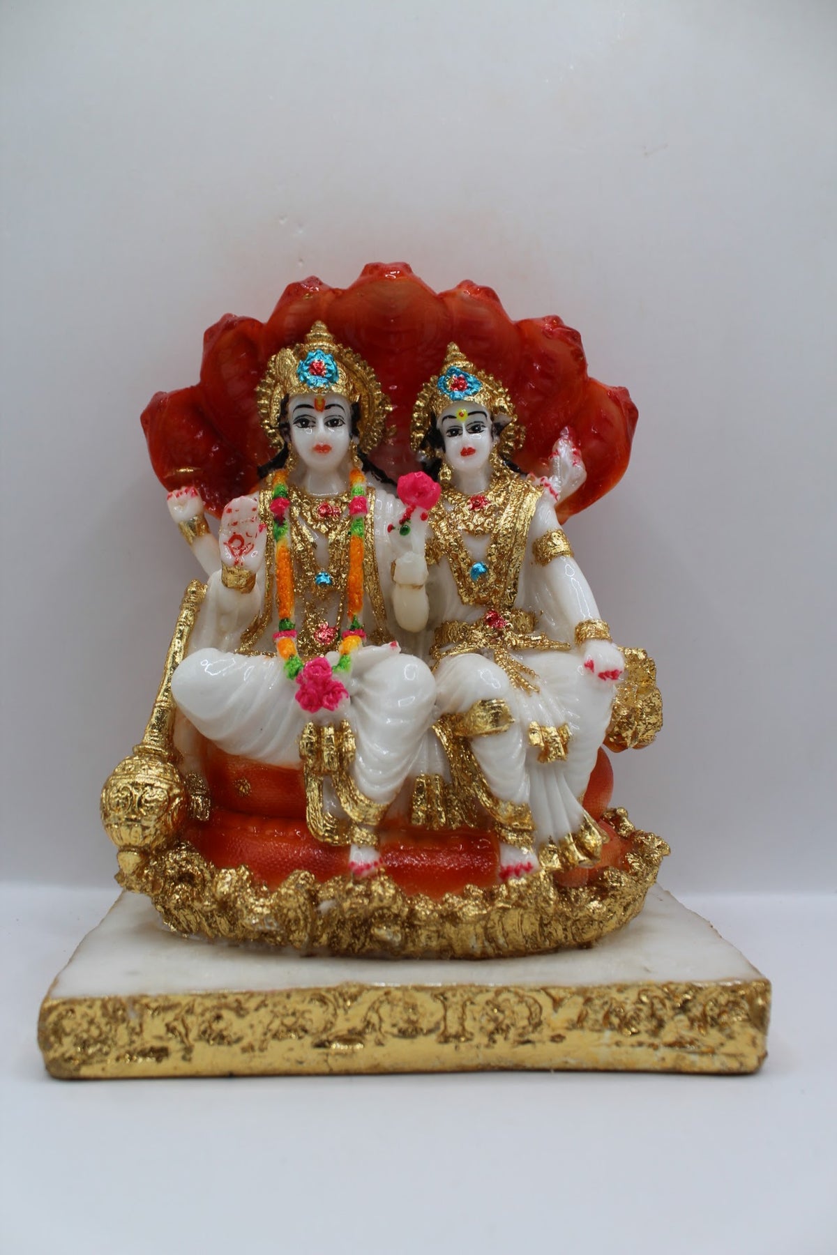 White and orange resin Vishnu Laxmi murti, seated under Sheshnaag, front view