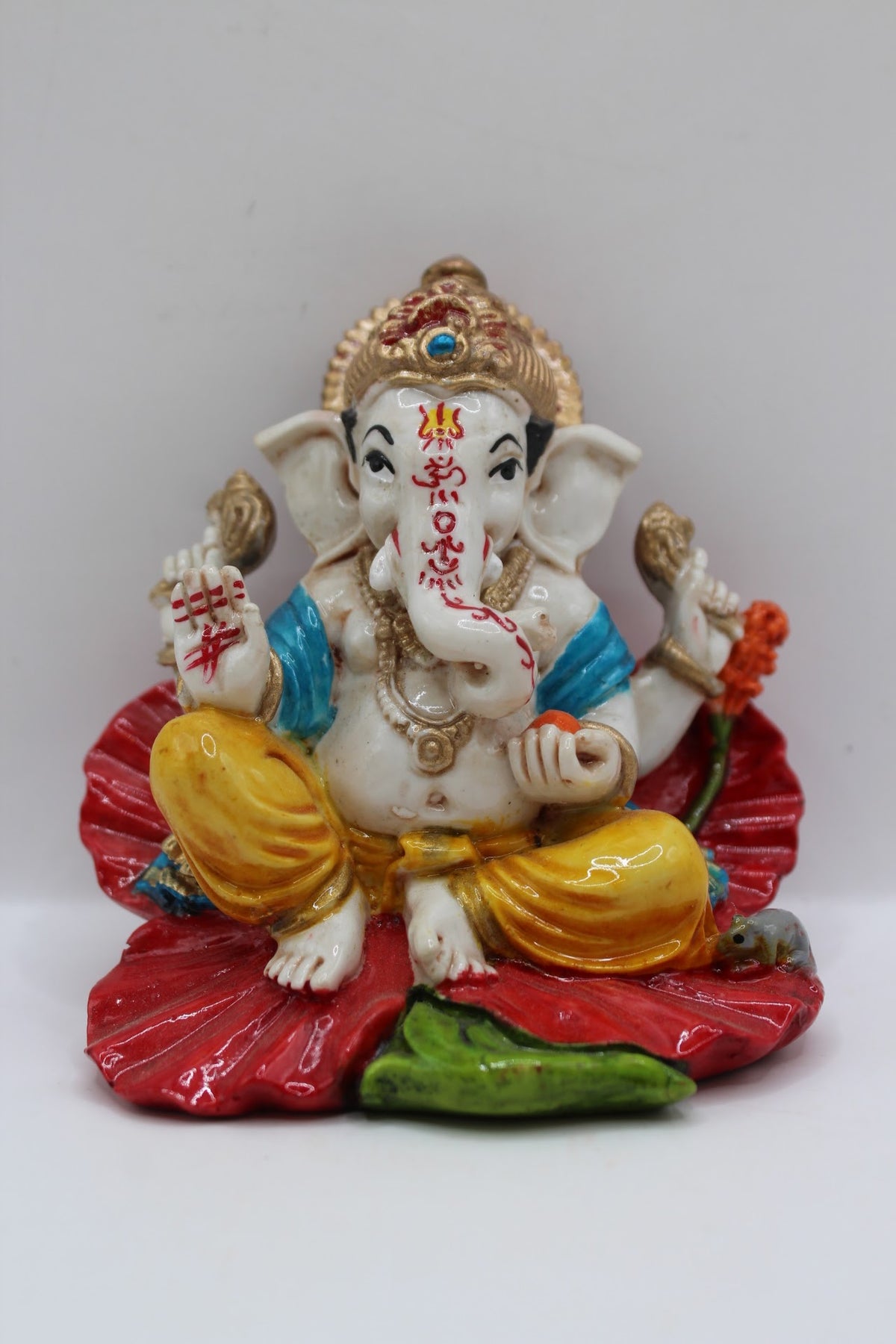 Resin Ganesh murti on red leaf, yellow dhoti, front view