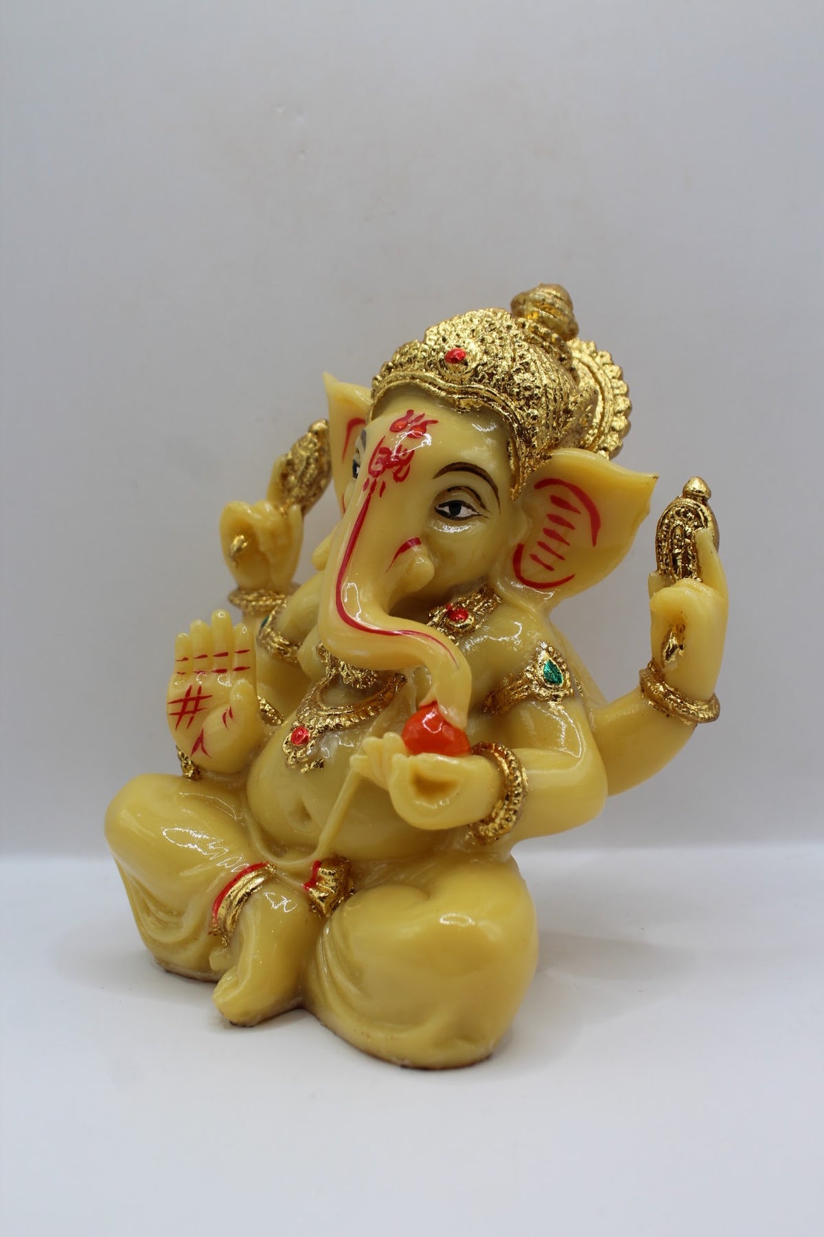 Cream resin Ganesh murti seated, gold crown, right side view