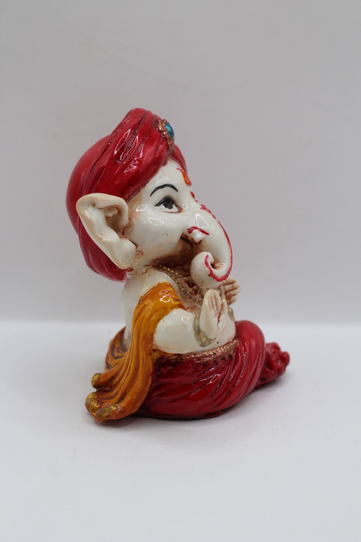 Baby Ganesh murti in red turban, blessing hand, left side view