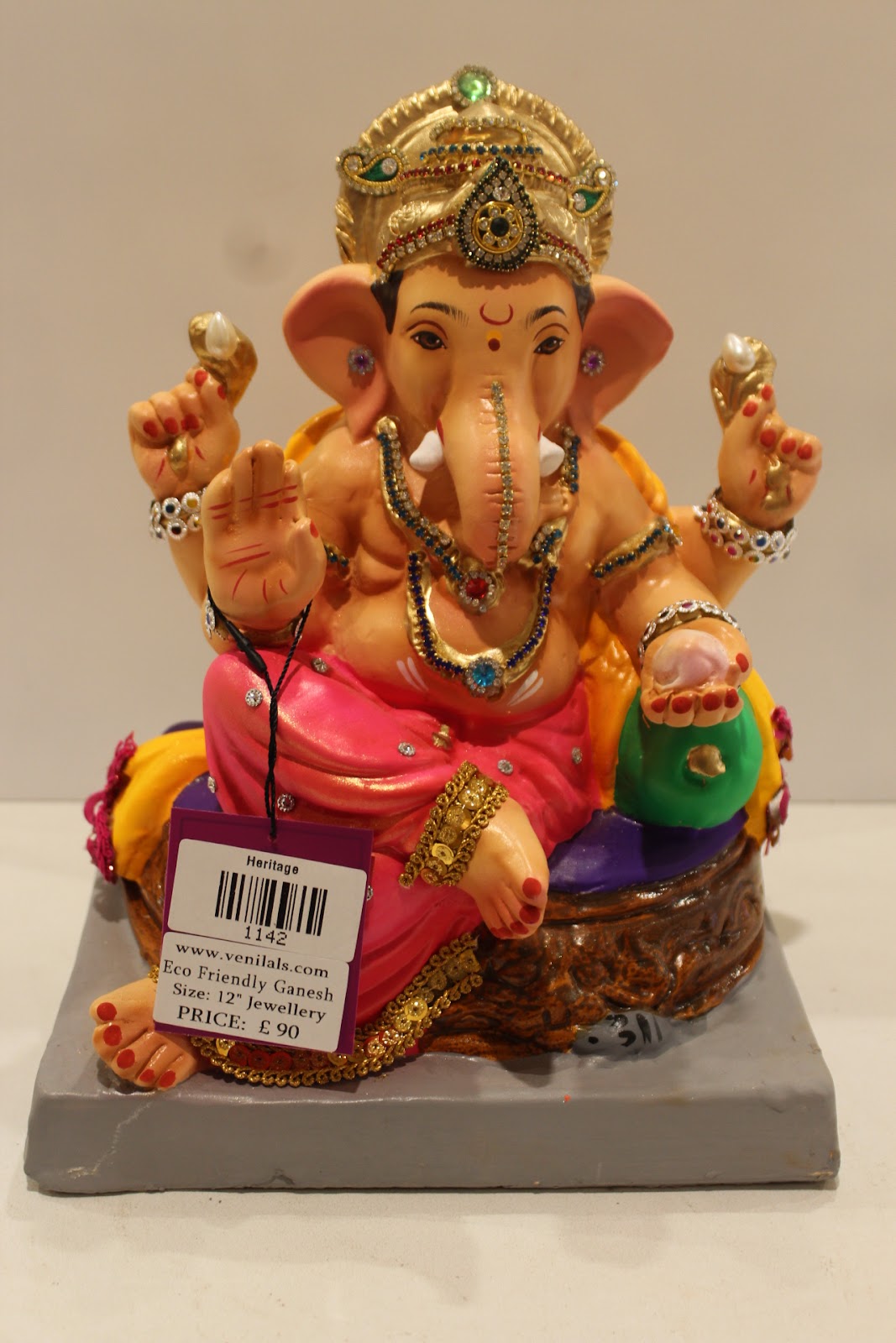 Eco-friendly clay Ganesh idol in jewellery style with rani pink dhoti and basket throne, front view