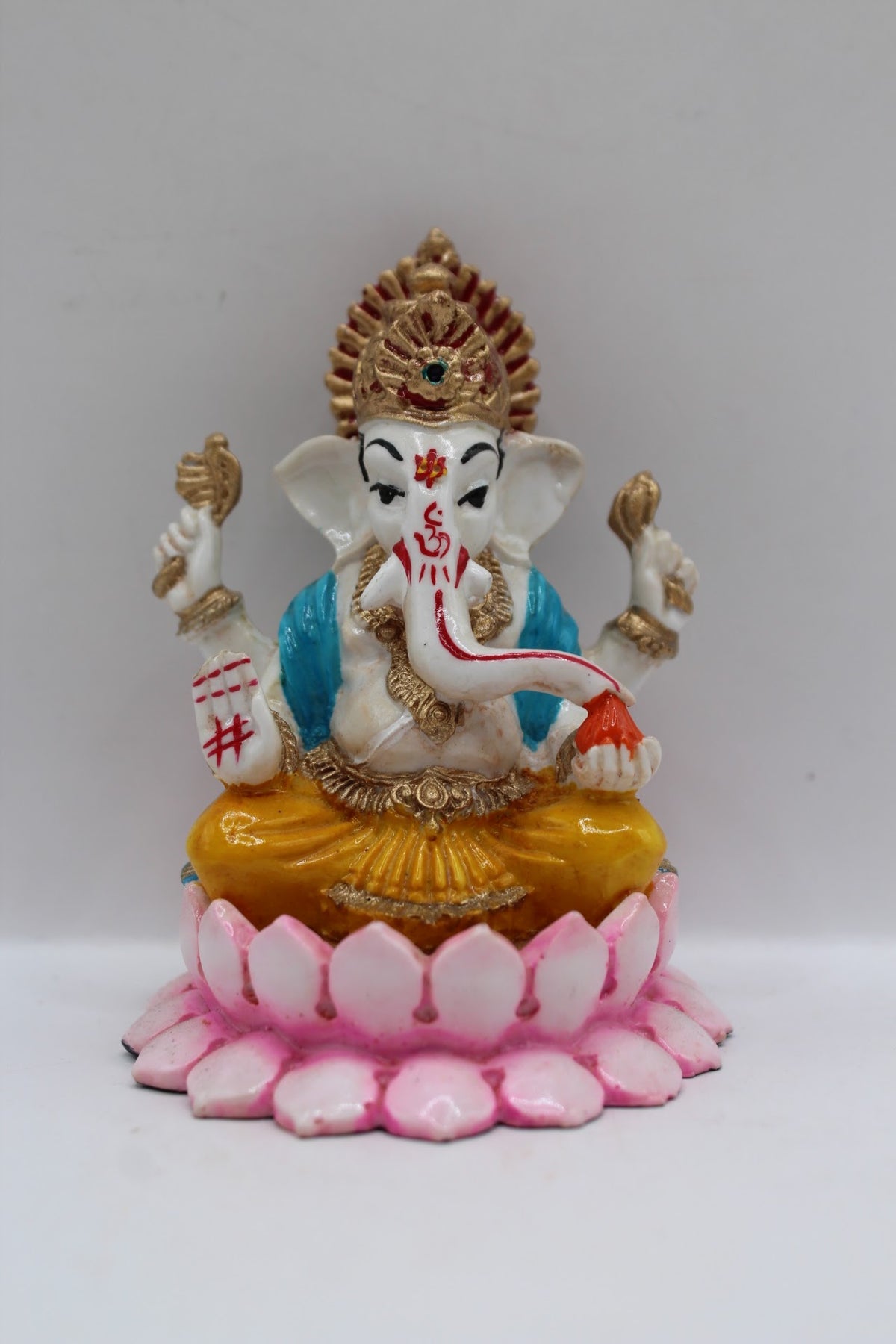 Resin Ganesh murti on pink lotus, yellow dhoti, front view