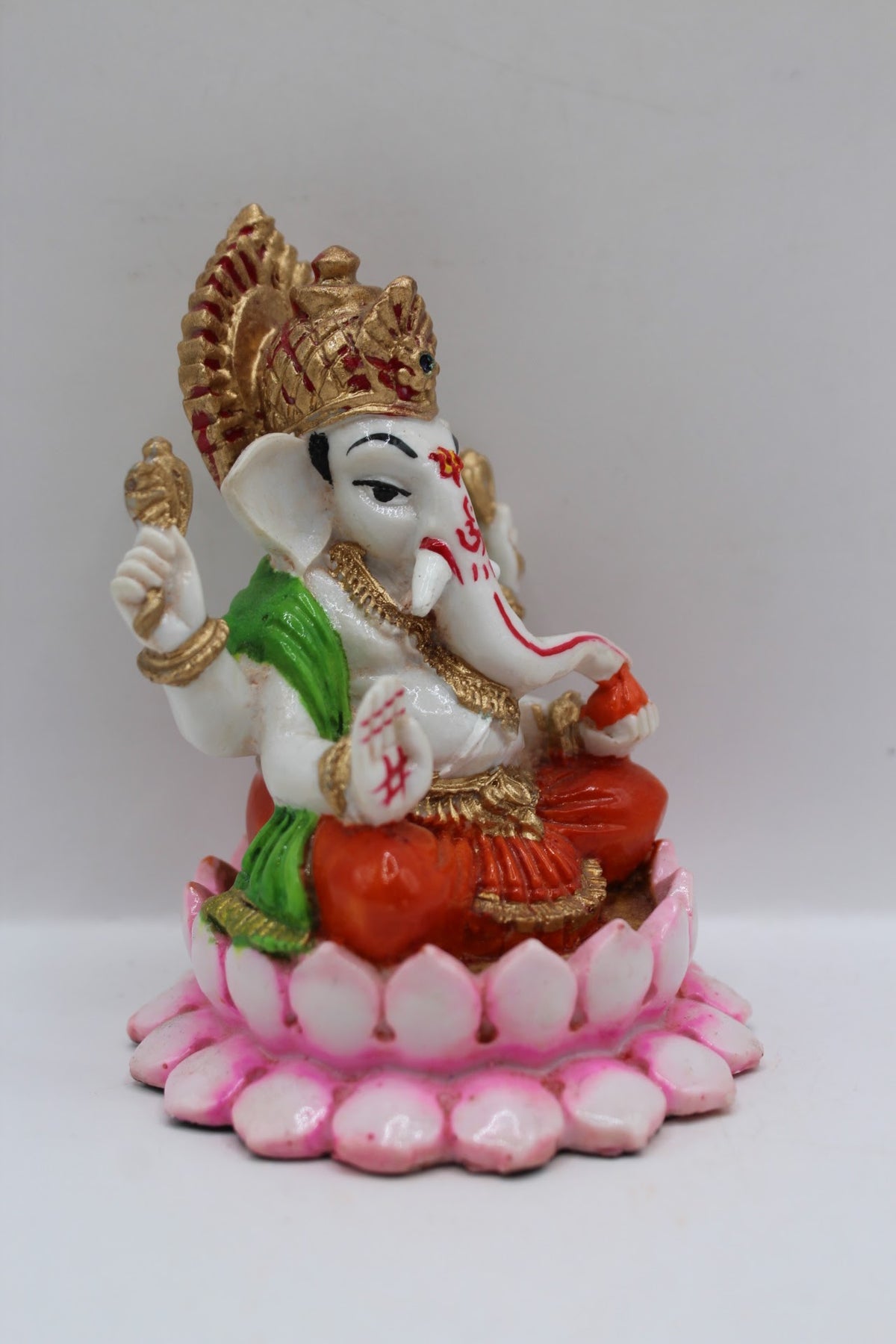 Resin Ganesh murti on pink lotus, orange dhoti, left side view