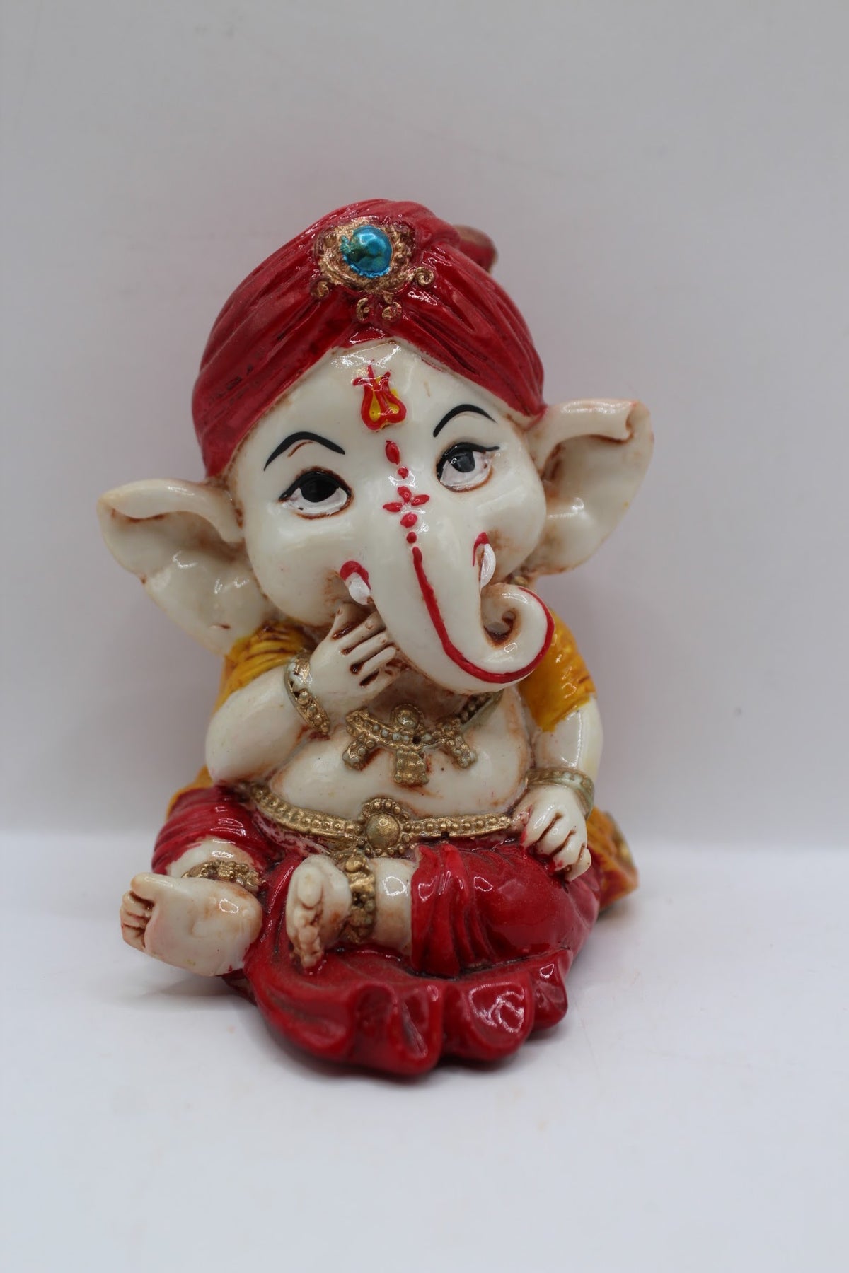 Baby Ganesh murti in red turban, finger to lips, front view