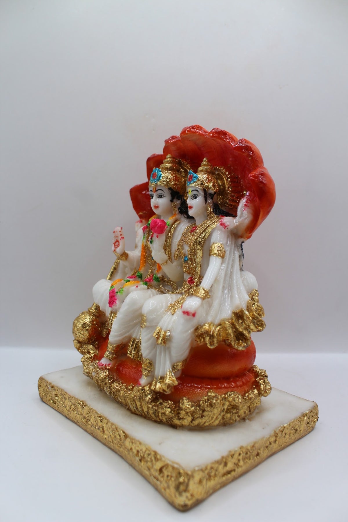 White and orange resin Vishnu Laxmi murti, seated under Sheshnaag, right side view