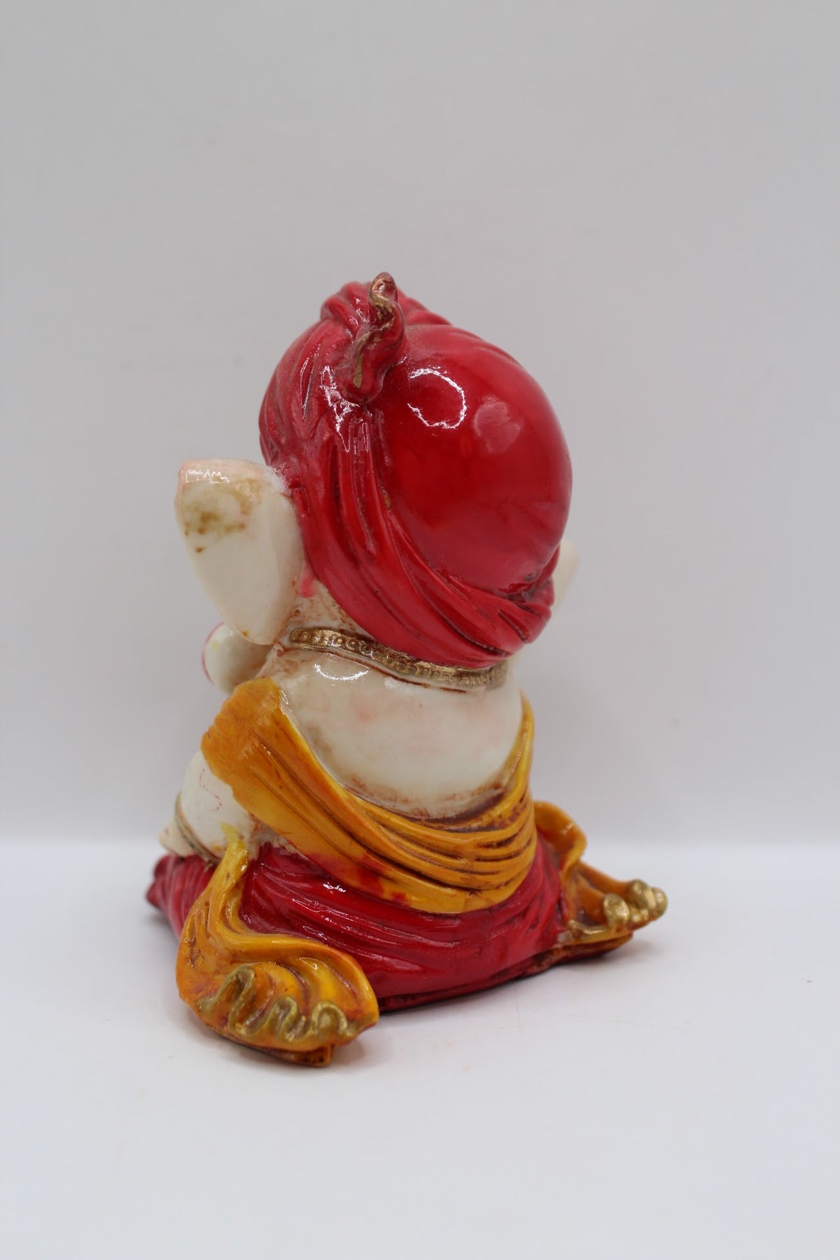 Baby Ganesh murti in red turban, finger to lips, back view