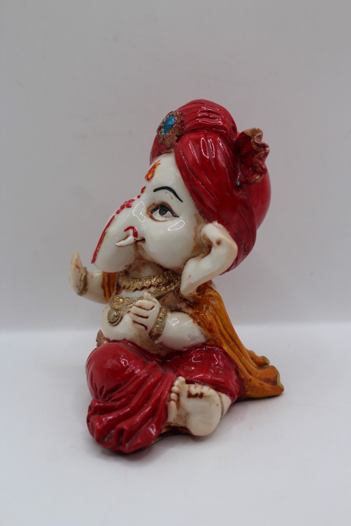 Baby Ganesh murti in red turban, blessing hand, right side view