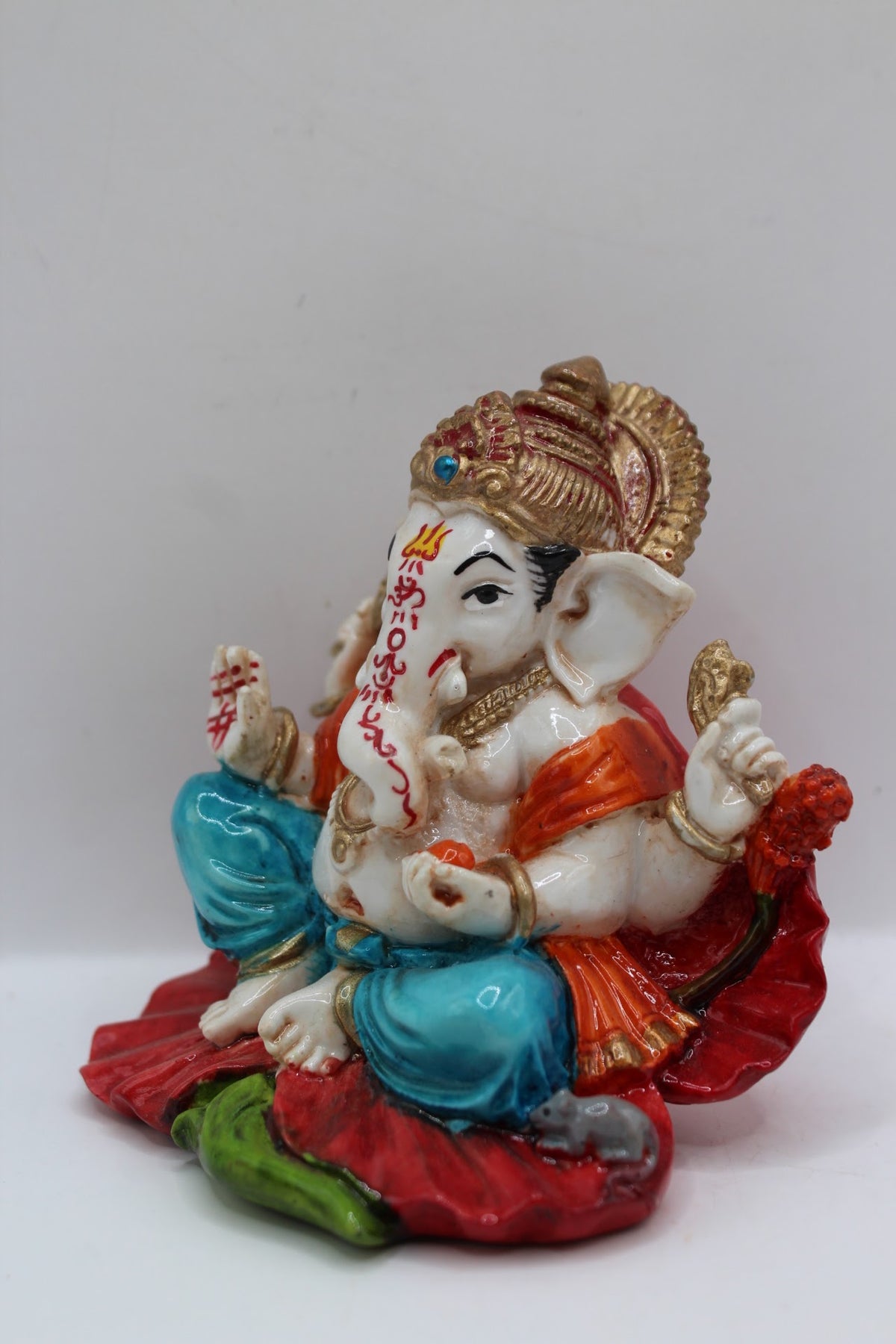 Resin Ganesh murti on red leaf, blue dhoti, right side view