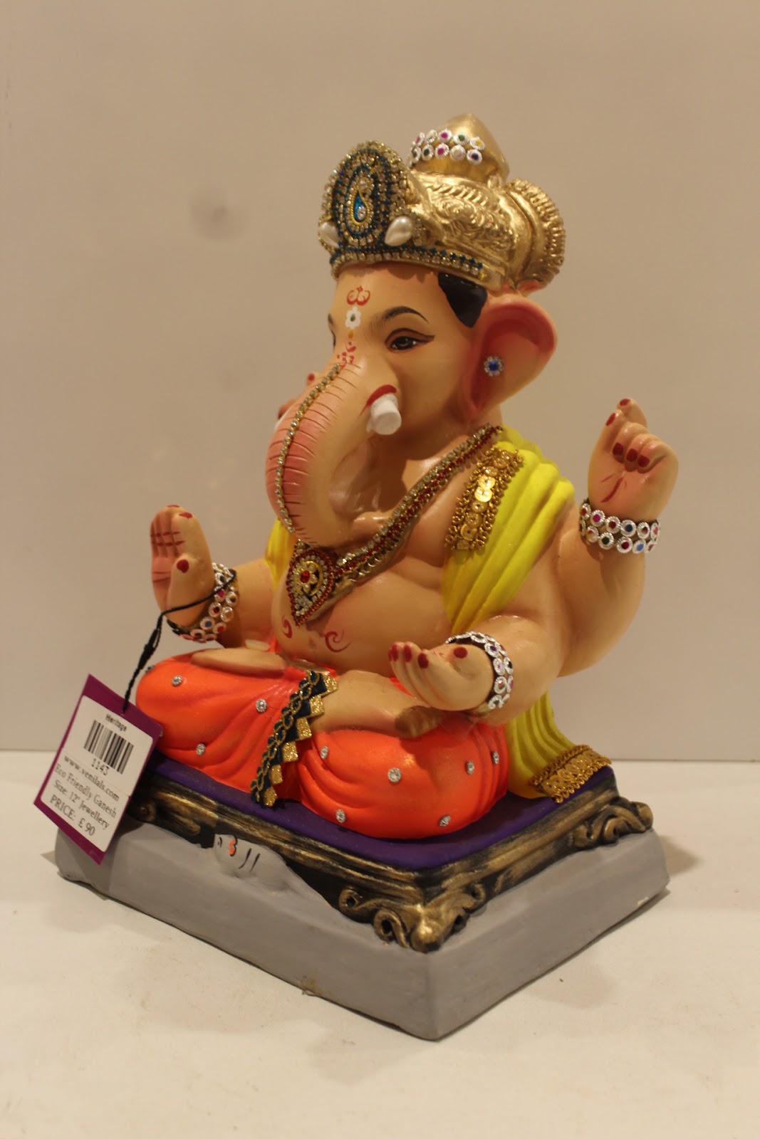 Eco-friendly clay Ganesh idol in jewellery style with yellow khes and orange dhoti, side view