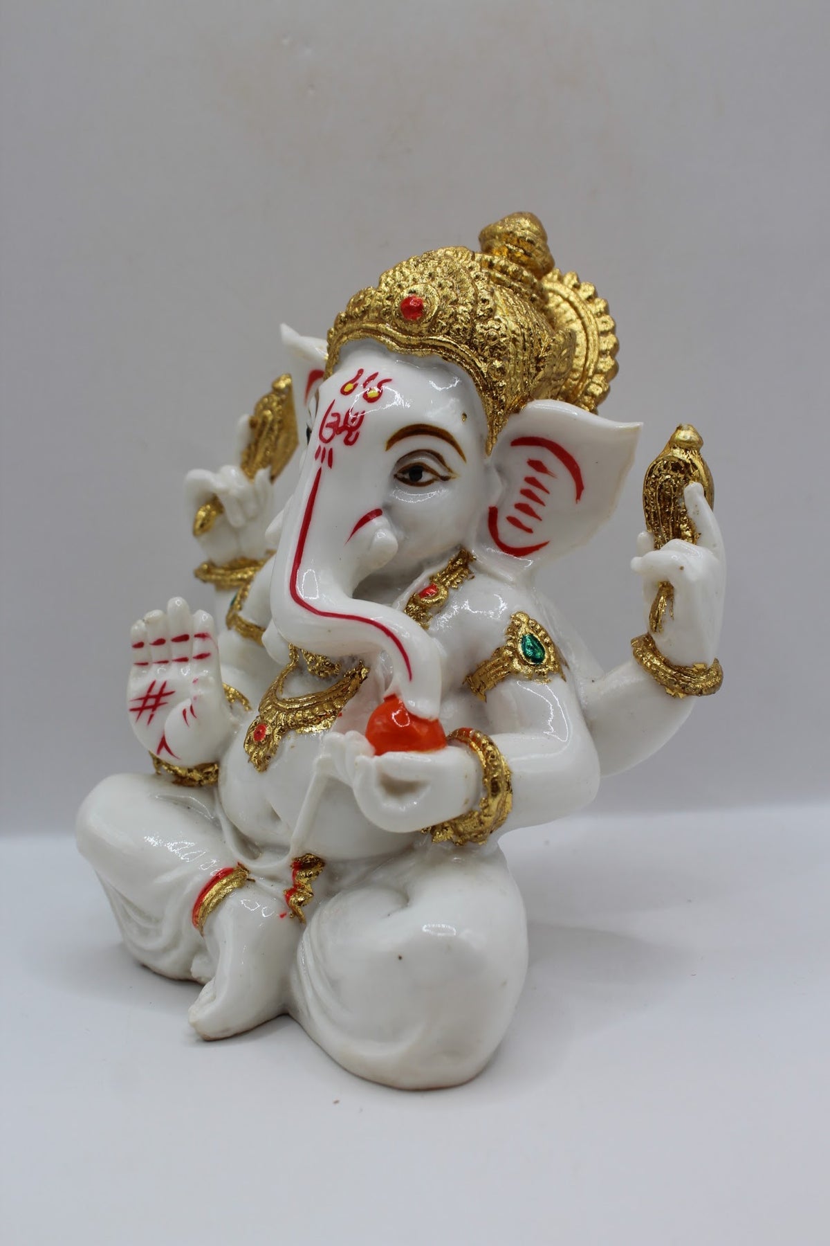 White and gold resin Ganesh murti seated, right side view