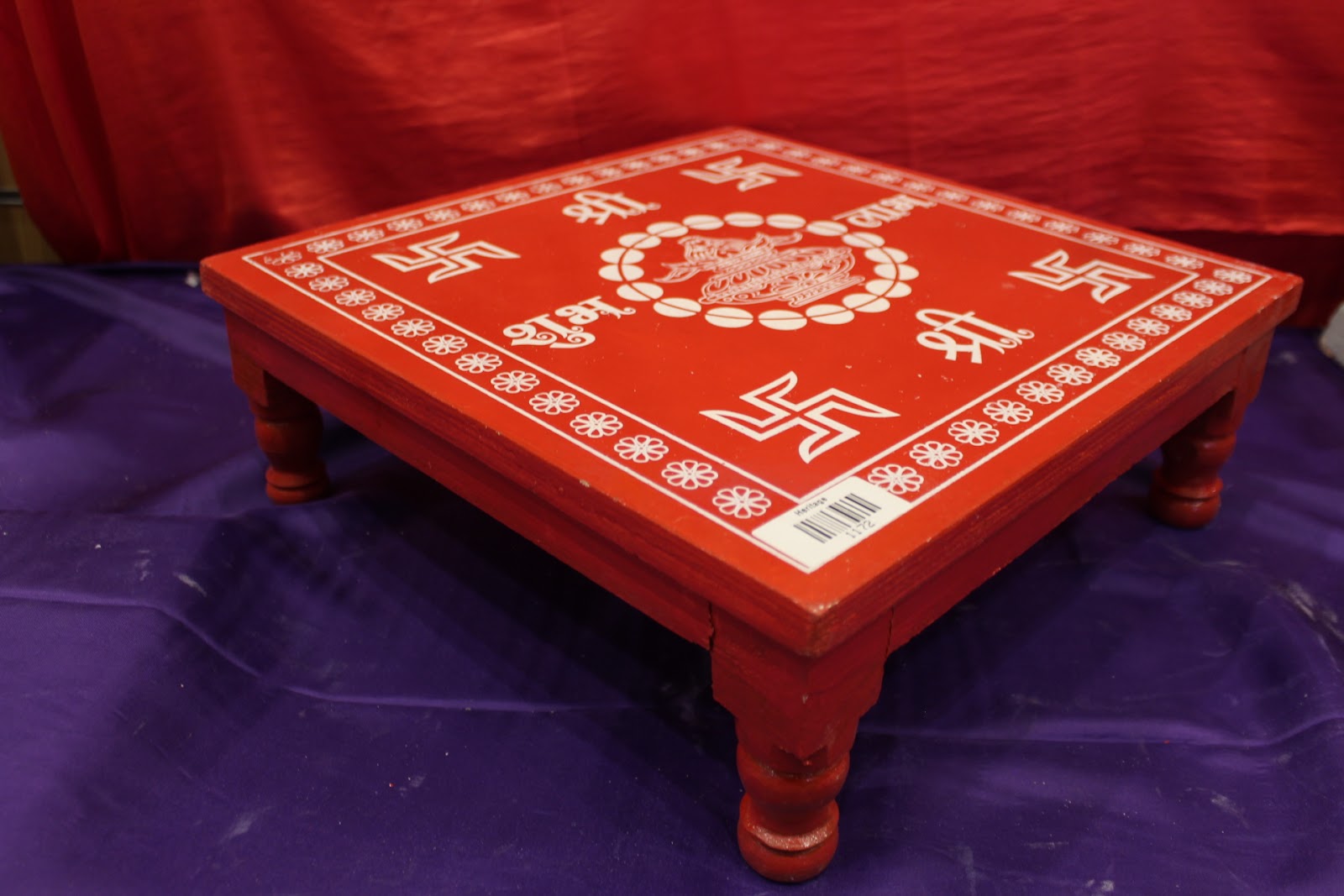 Red wooden bajot pooja chowki angled view showing turned legs
