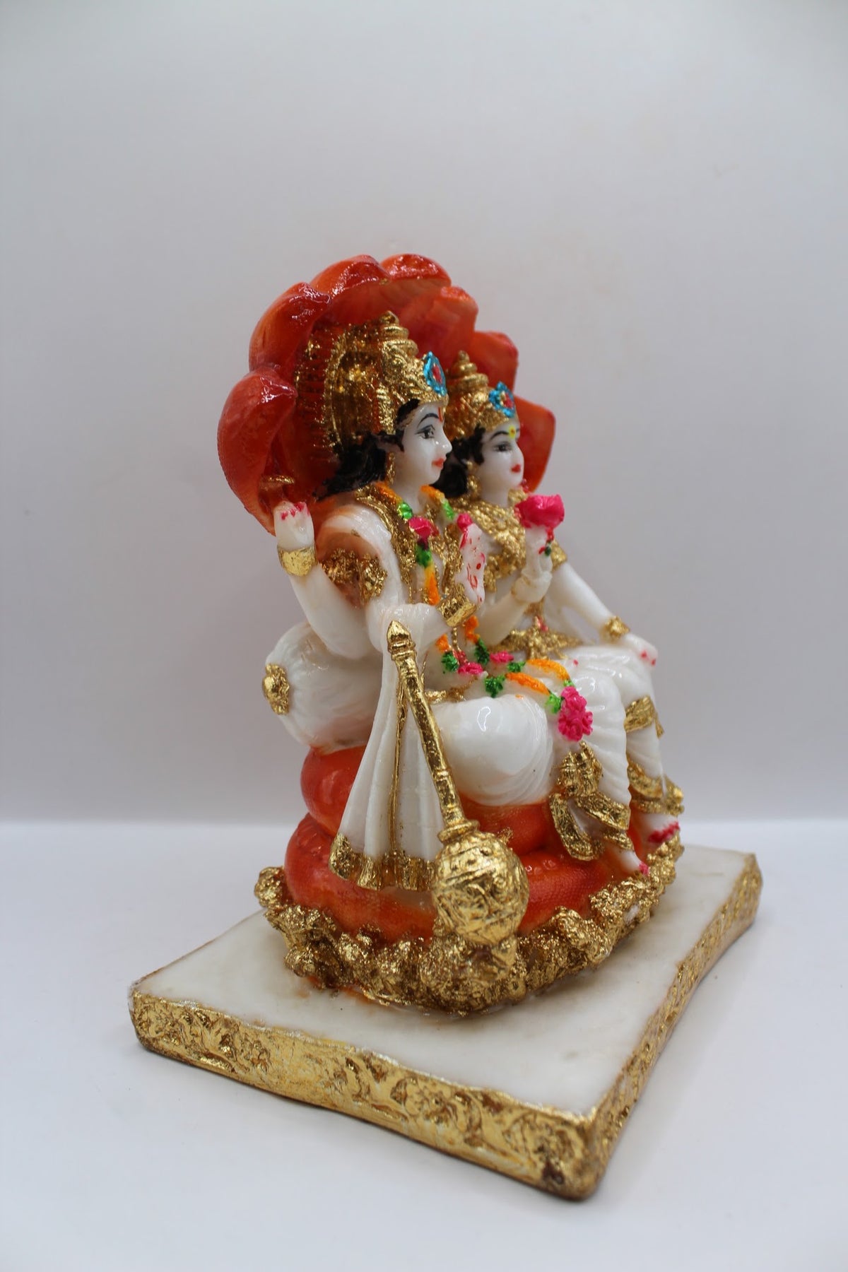 White and orange resin Vishnu Laxmi murti, seated under Sheshnaag, left side view