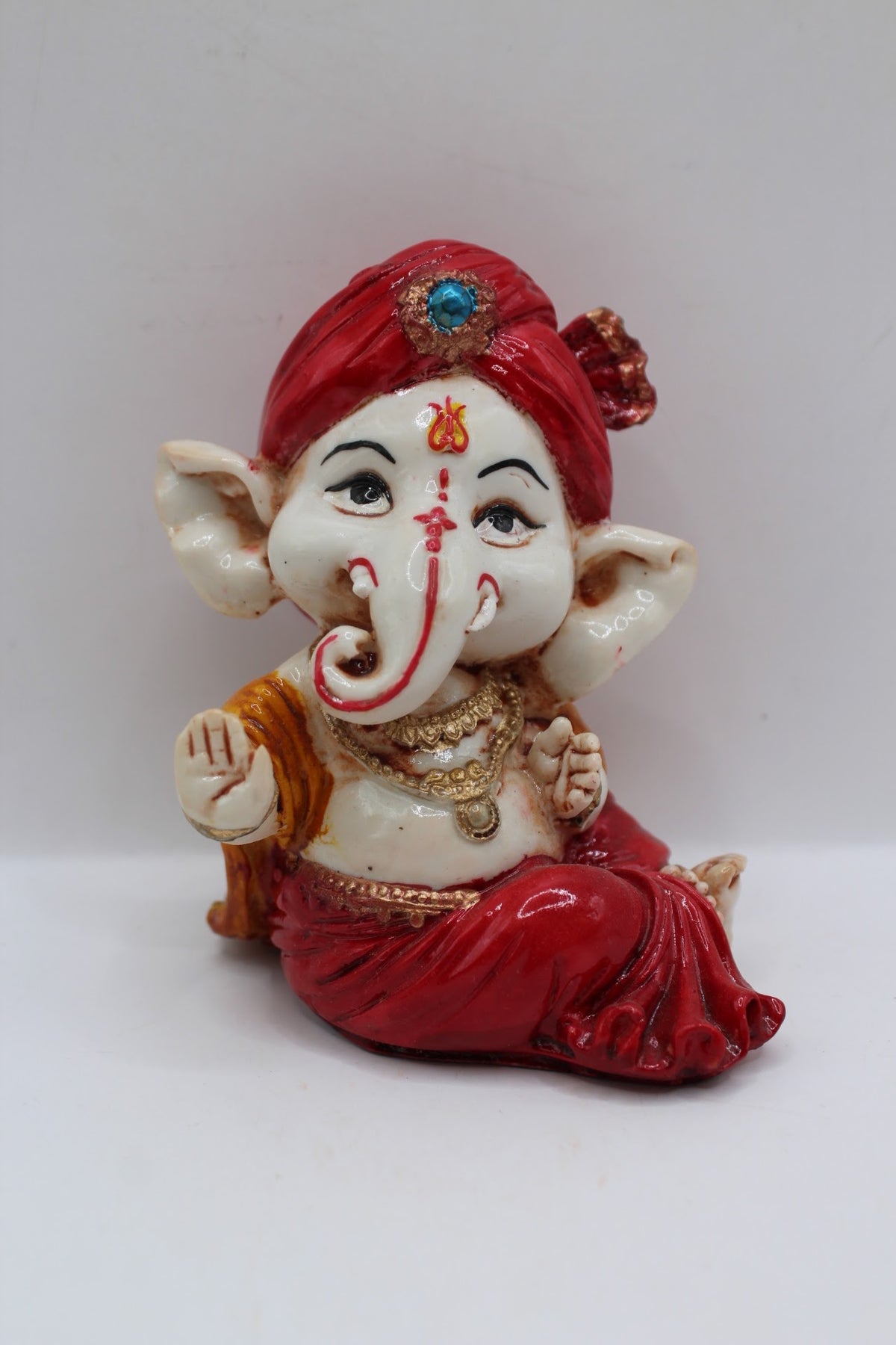 Baby Ganesh murti in red turban, blessing hand, front view