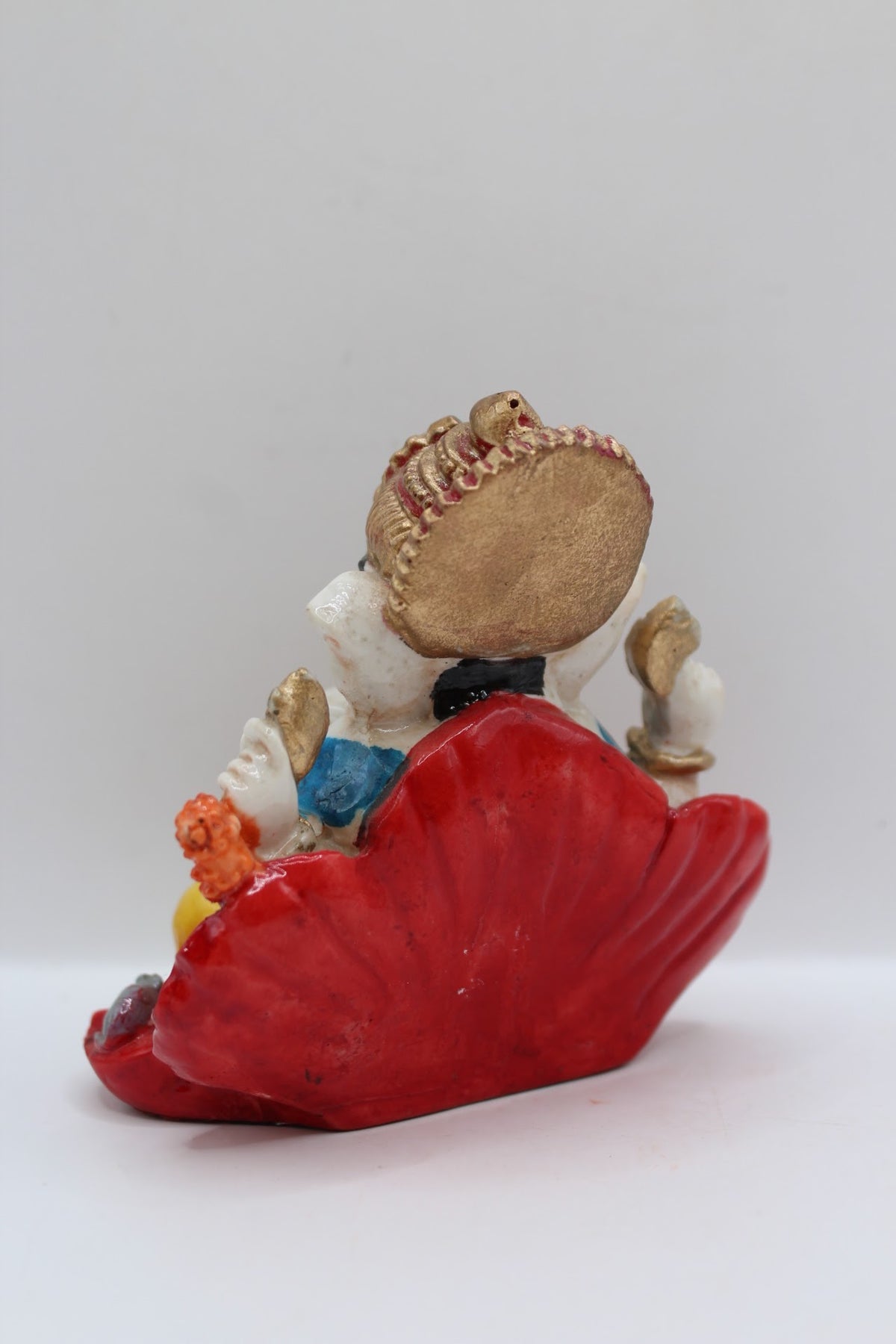 Resin Ganesh murti on red leaf, yellow dhoti, back view