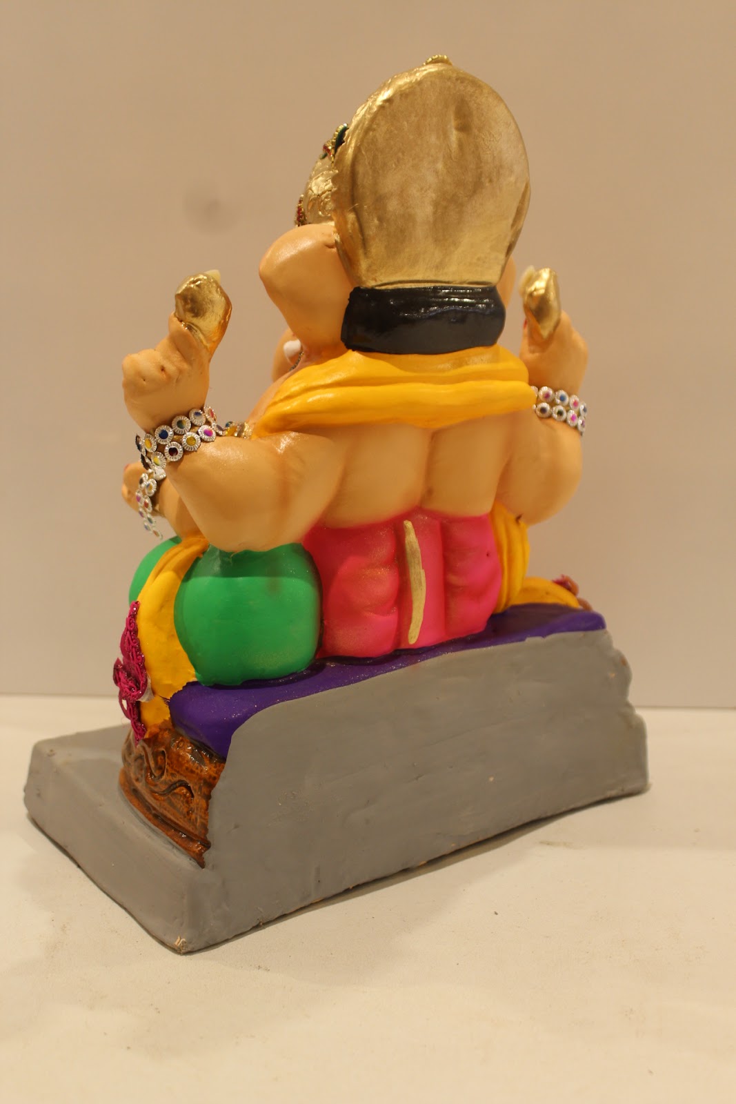 Eco-friendly clay Ganesh idol in jewellery style with rani pink dhoti and basket throne, back view