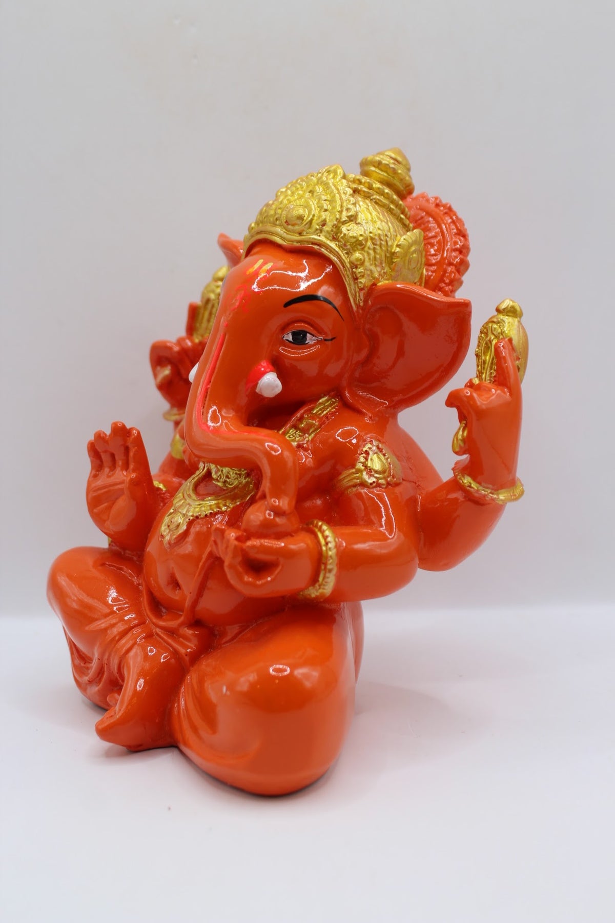 Orange resin Ganesh murti seated, gold crown, right side view