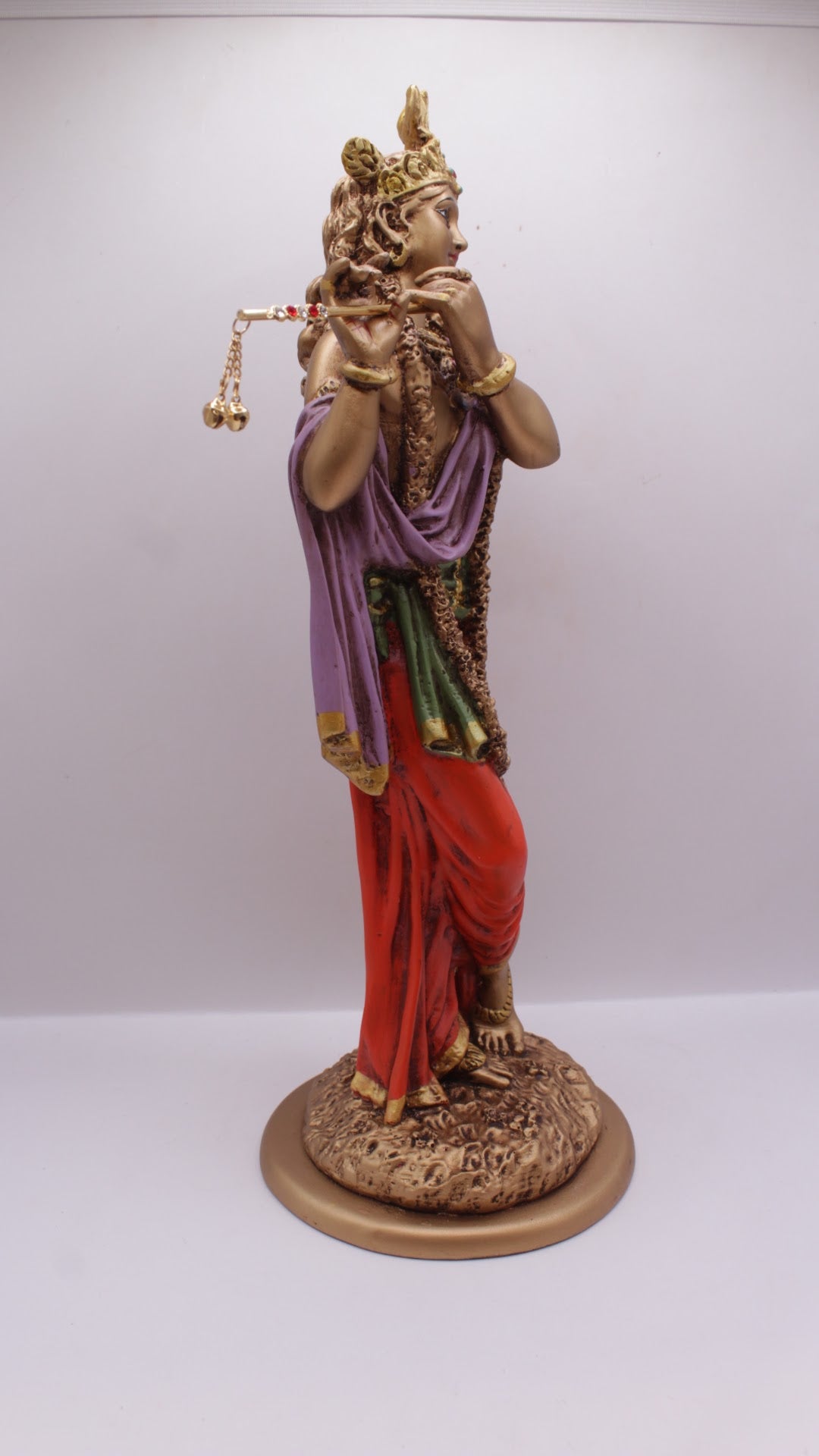 Painted resin Krishna statue playing flute, left side view