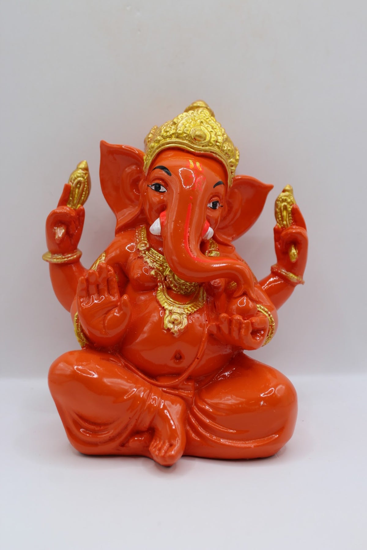 Orange resin Ganesh murti seated, gold crown, front view