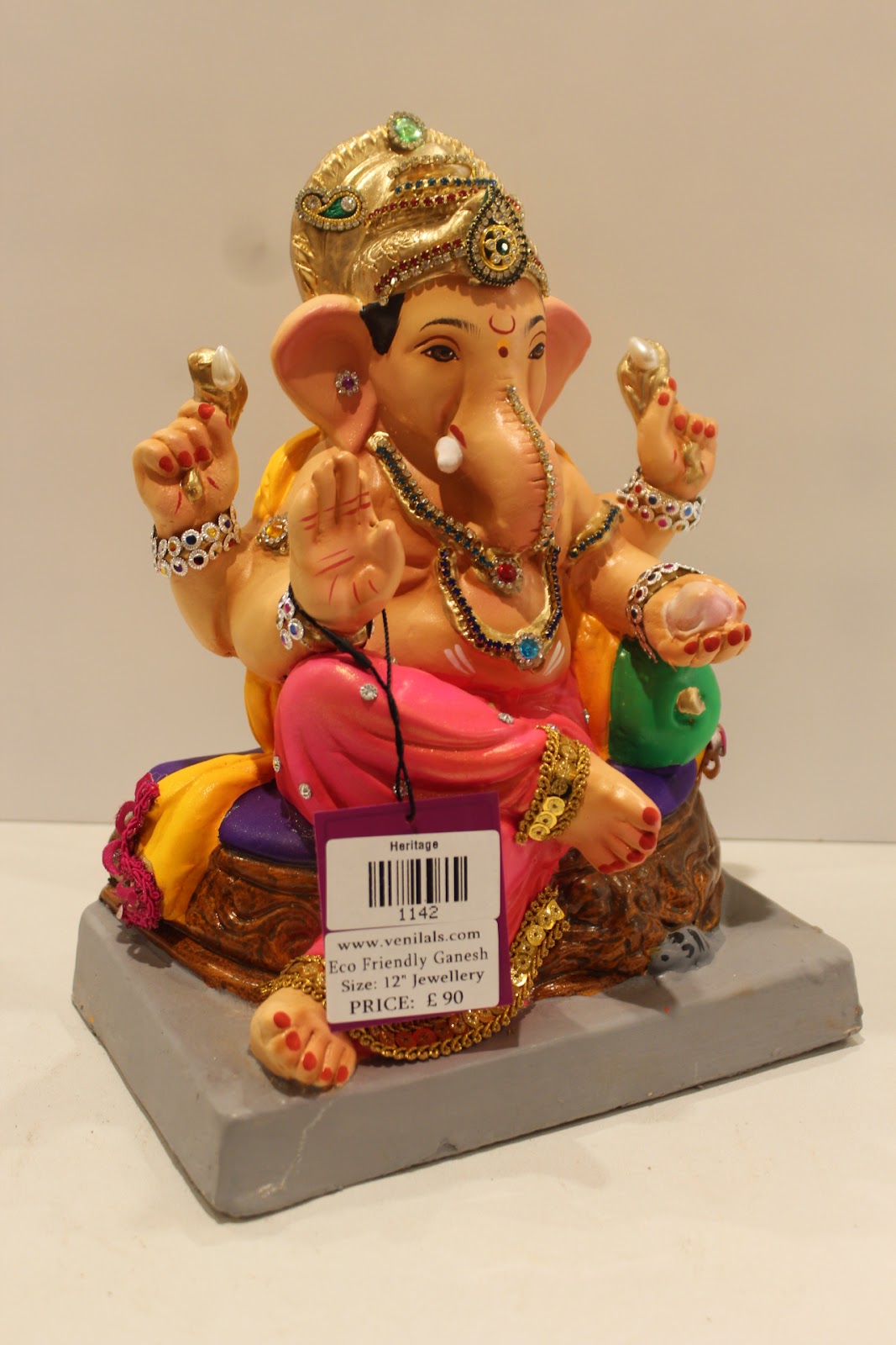 Eco-friendly clay Ganesh idol in jewellery style with rani pink dhoti and basket throne, side view