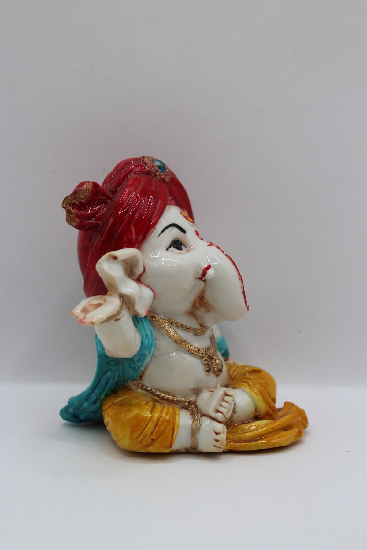 Baby Ganesh murti, red turban and blue scarf, left side view