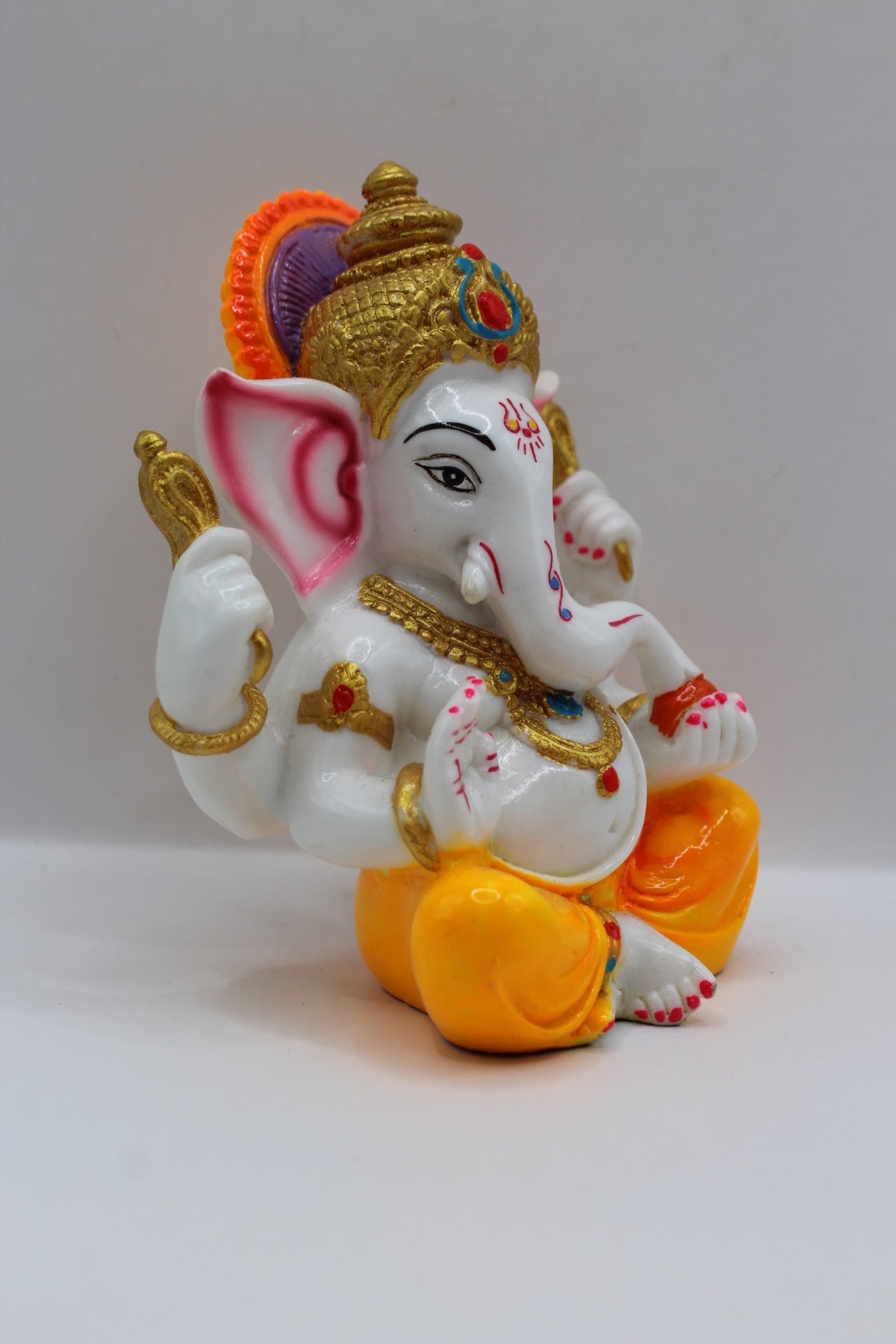 White resin Ganesh murti, yellow dhoti, left side view