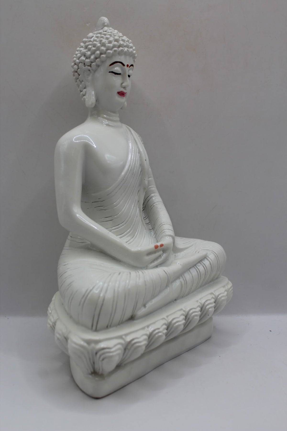 White resin Buddha statue meditating on a lotus base, left side view