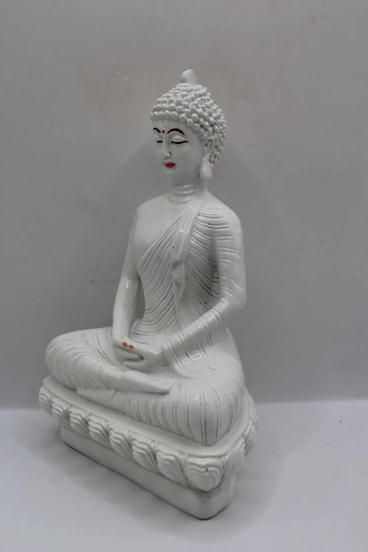 White resin Buddha statue meditating on a lotus base, right side view