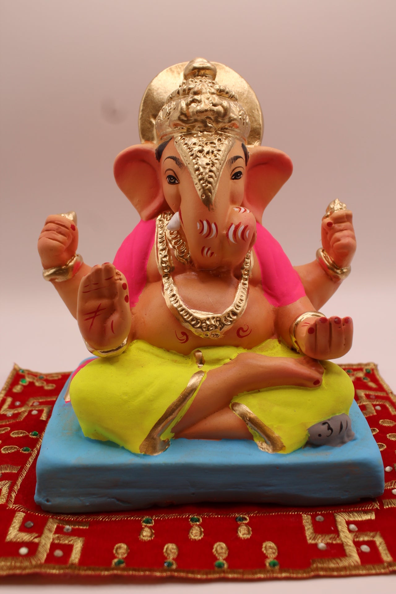 Eco-friendly 8 inch Ganesh Visarjan idol in pink shawl and lime dhoti with gold halo crown – front view