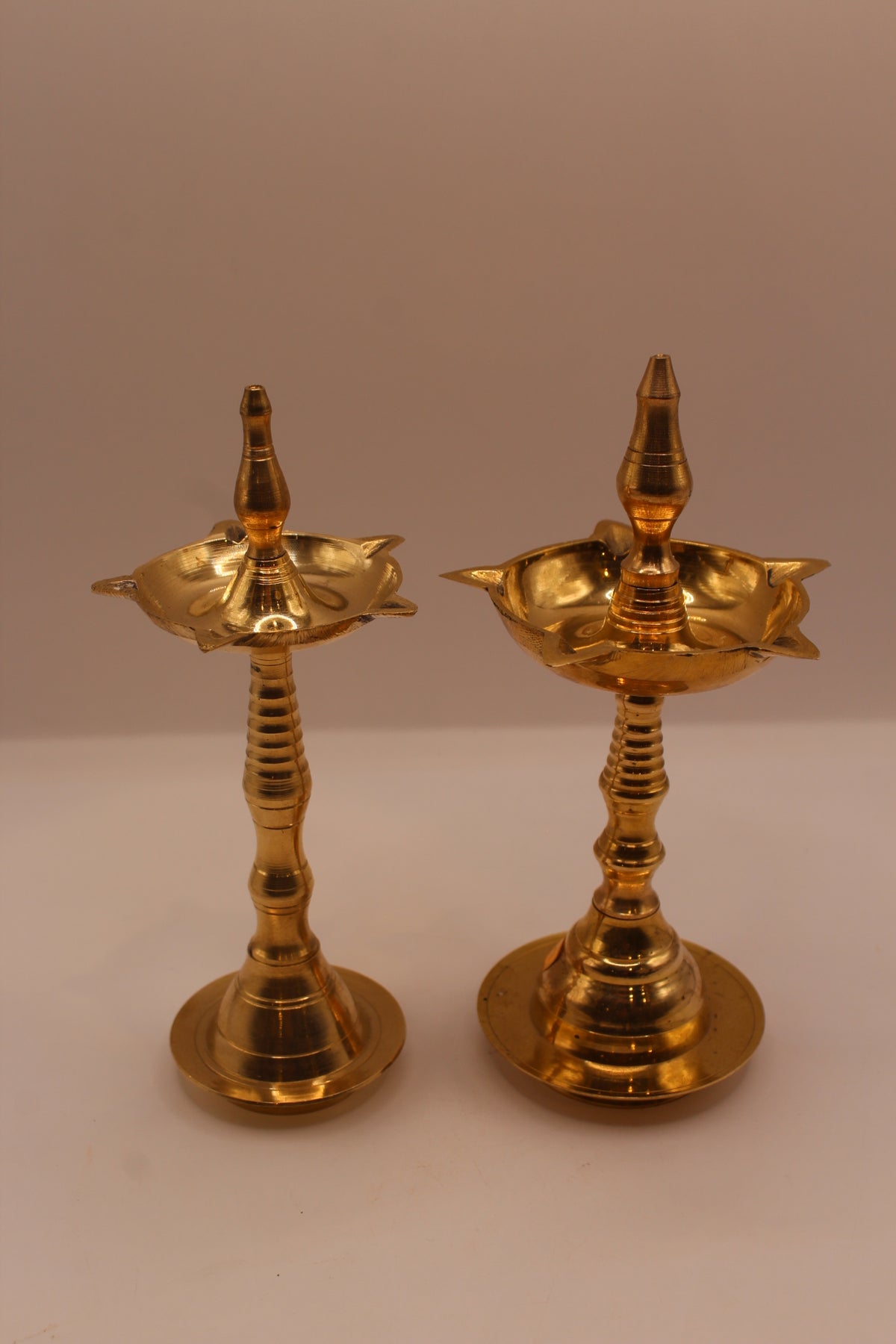 Slim and wide brass samai diya stands side by side