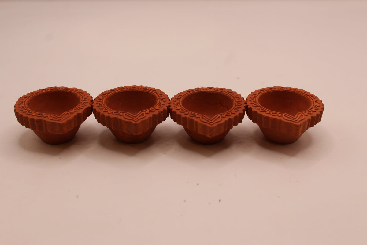 Four clay diyas in a row, front