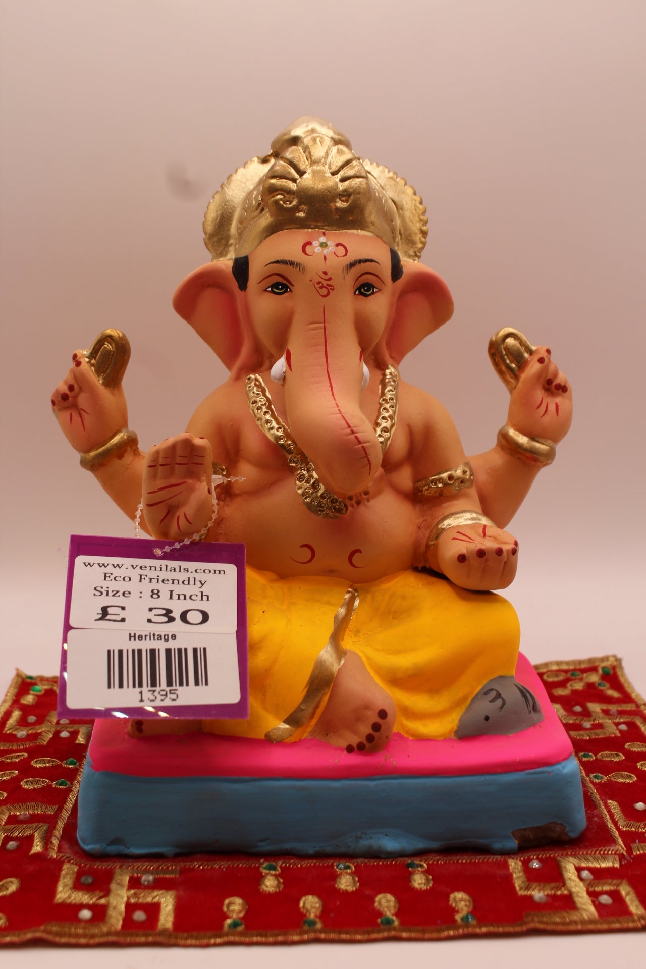 8 inch eco-friendly Ganesh idol – yellow dhoti and carved gold mukut on a pink mat, front