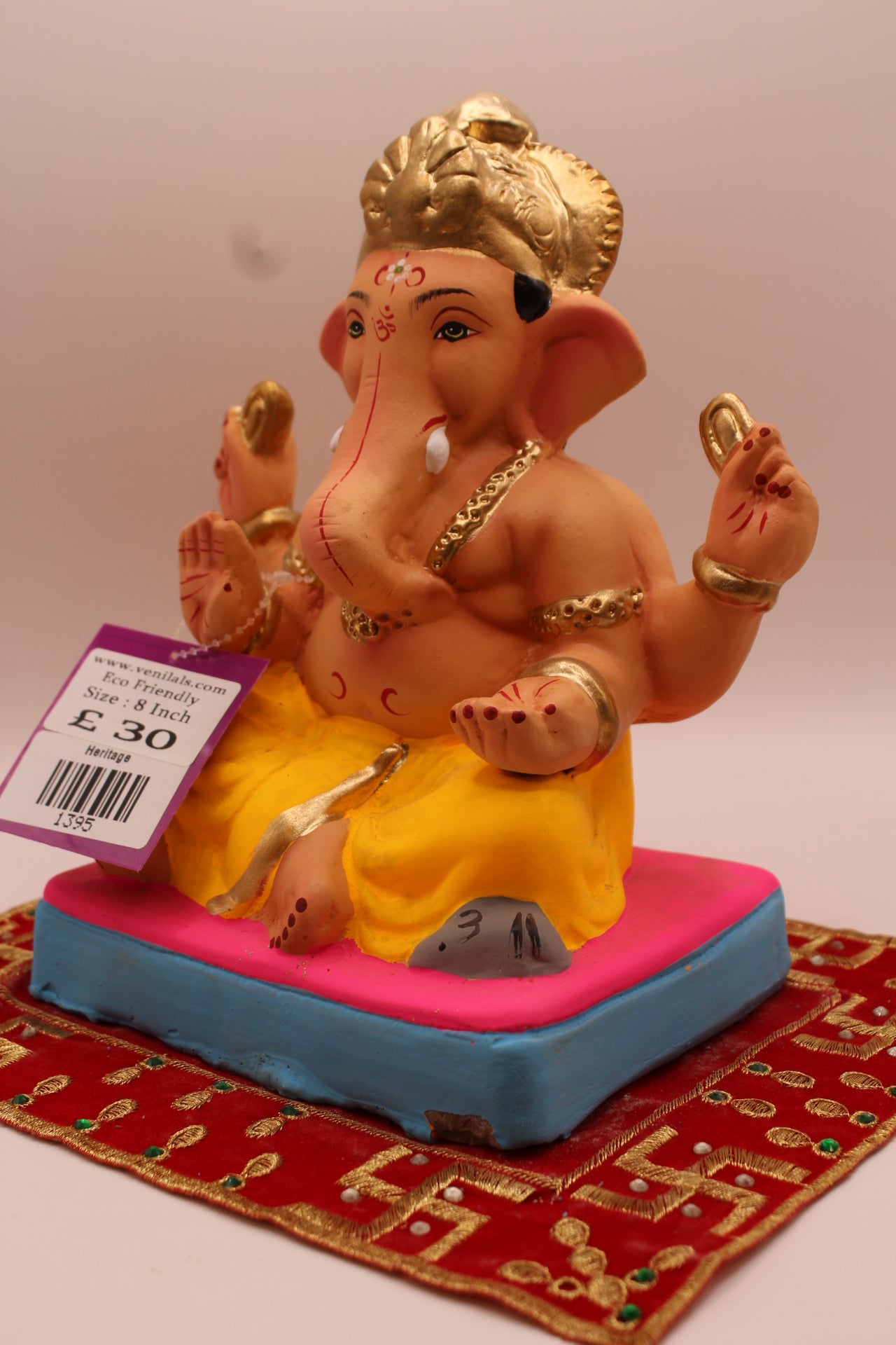 Angled view – yellow dhoti and carved gold mukut on a pink mat