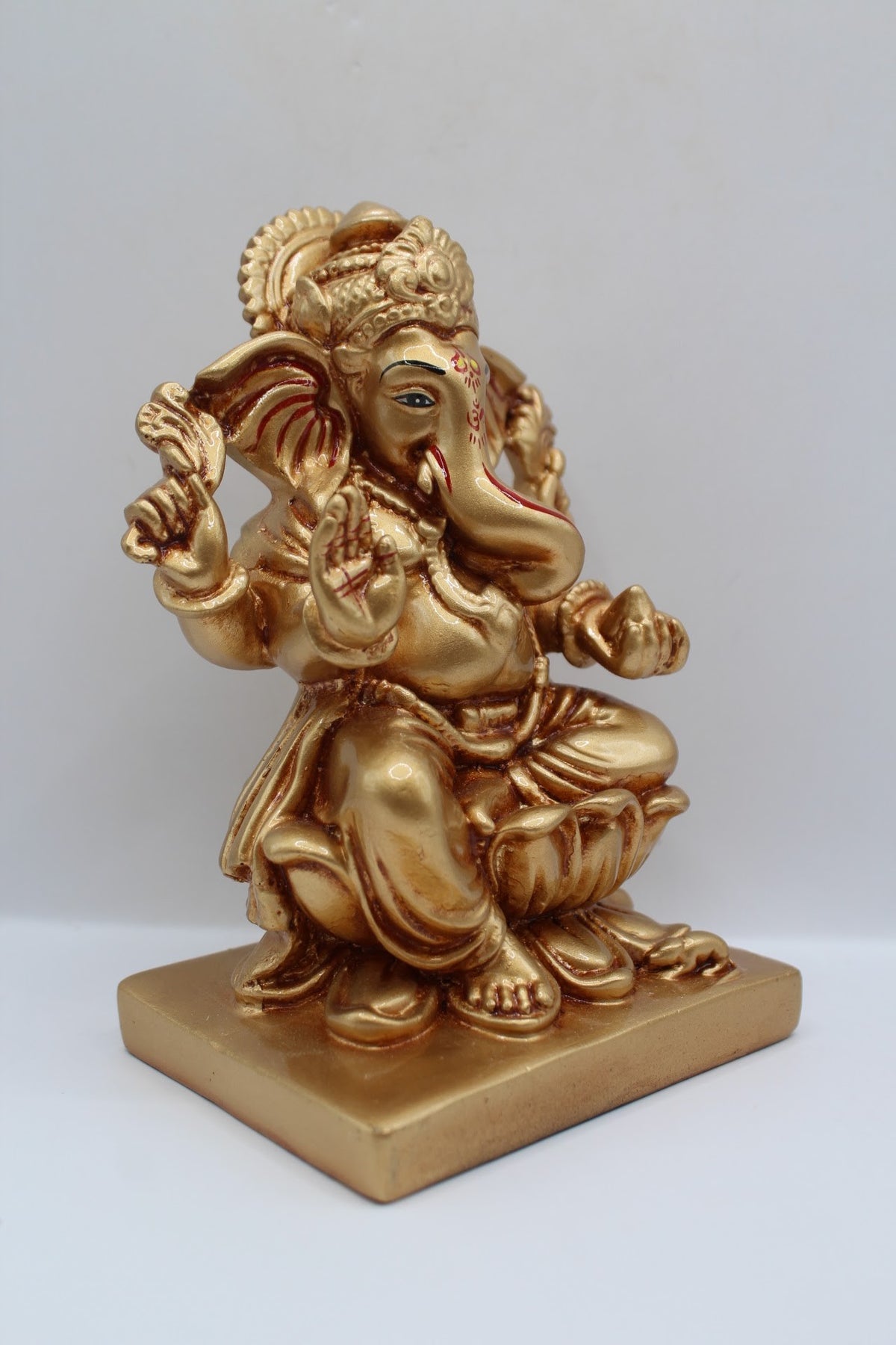 Gold resin Ganesh murti seated on a lotus, left side view