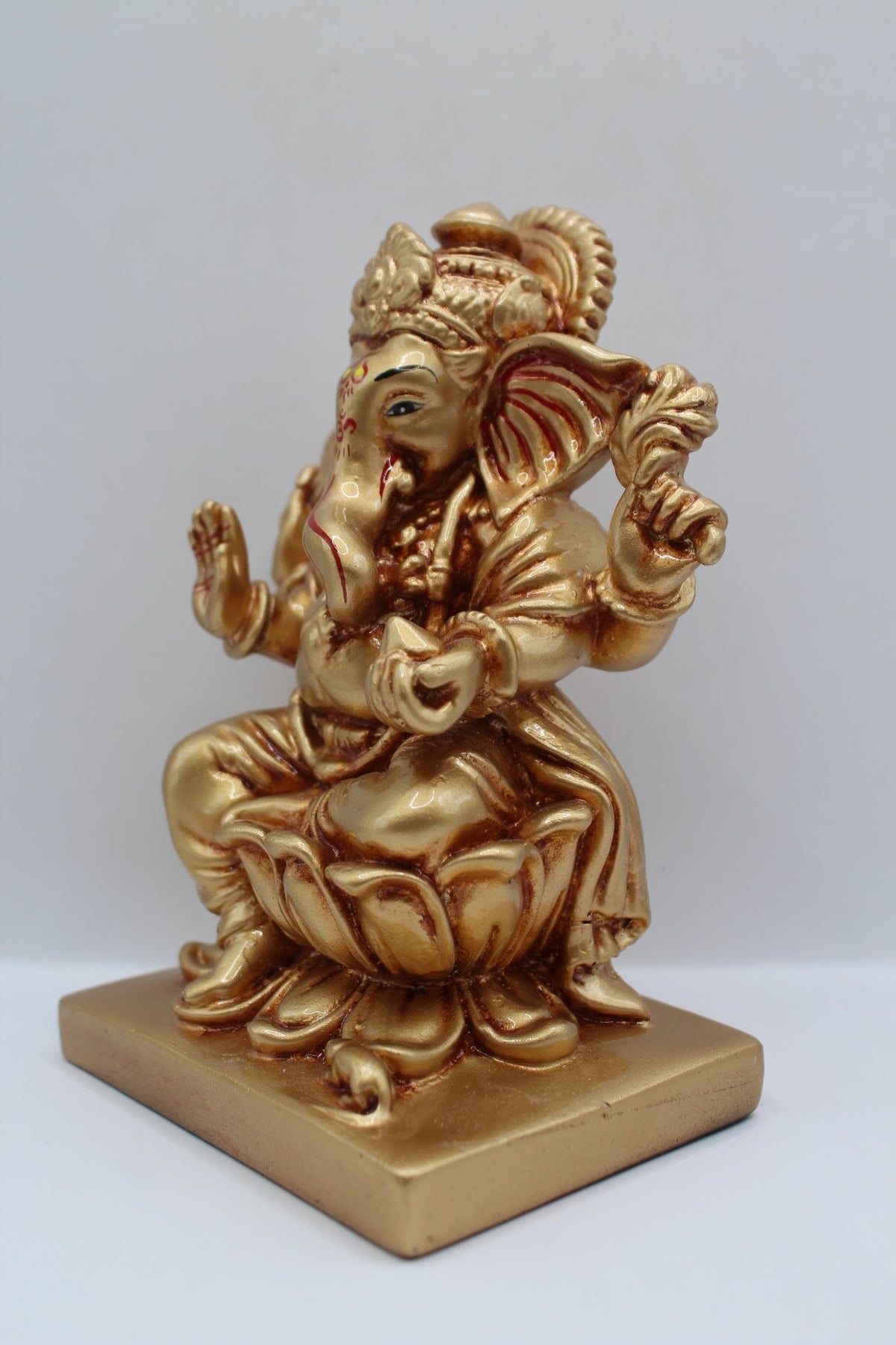 Gold resin Ganesh murti seated on a lotus, right side view