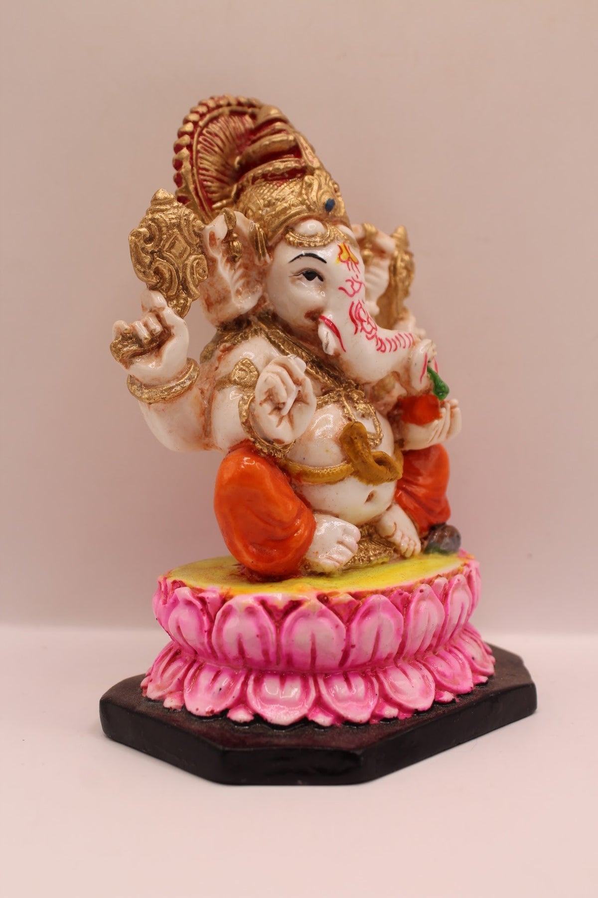 Resin Ganesh murti on pink lotus with orange dhoti, left side view