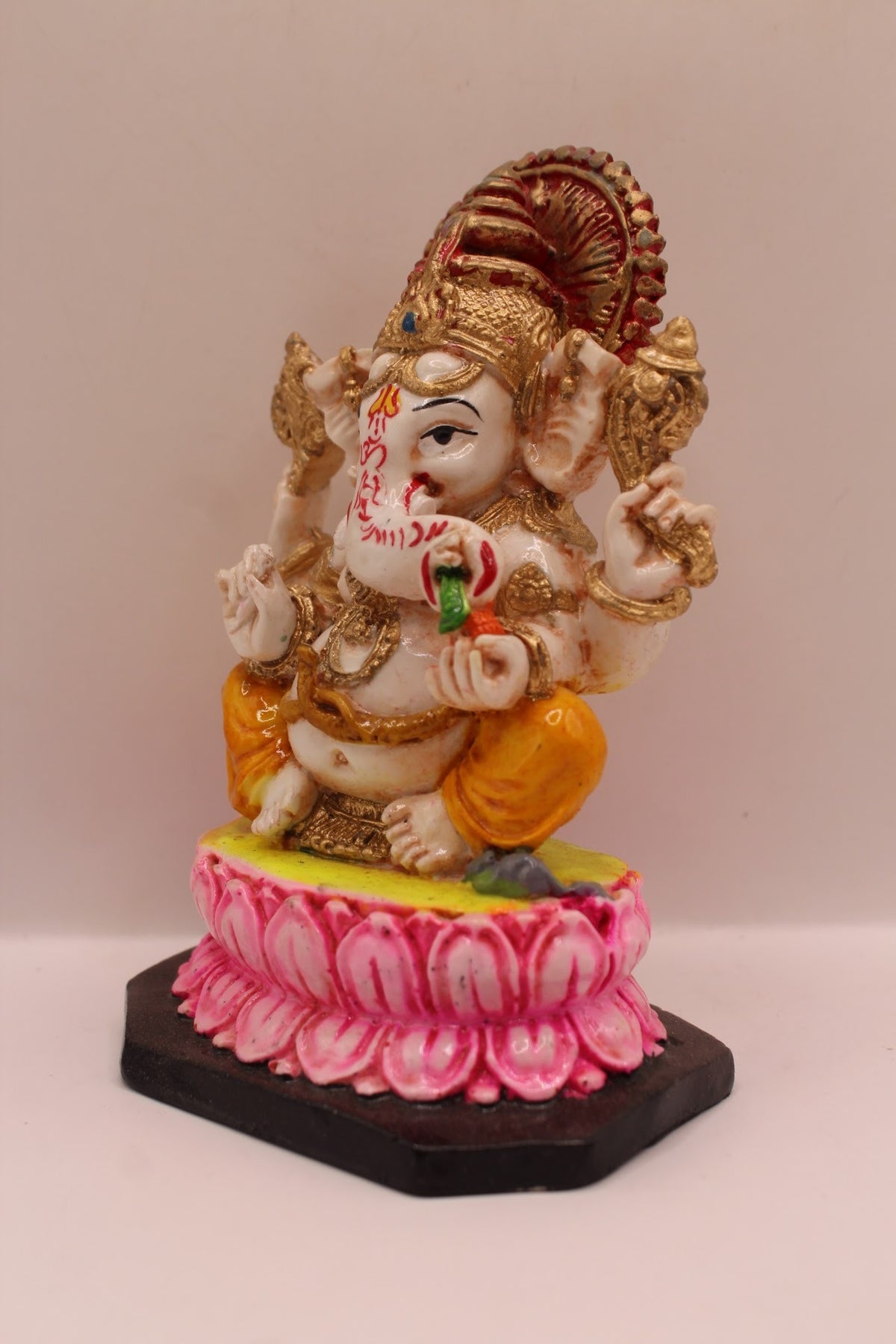 Resin Ganesh murti on pink lotus with yellow dhoti, right side view