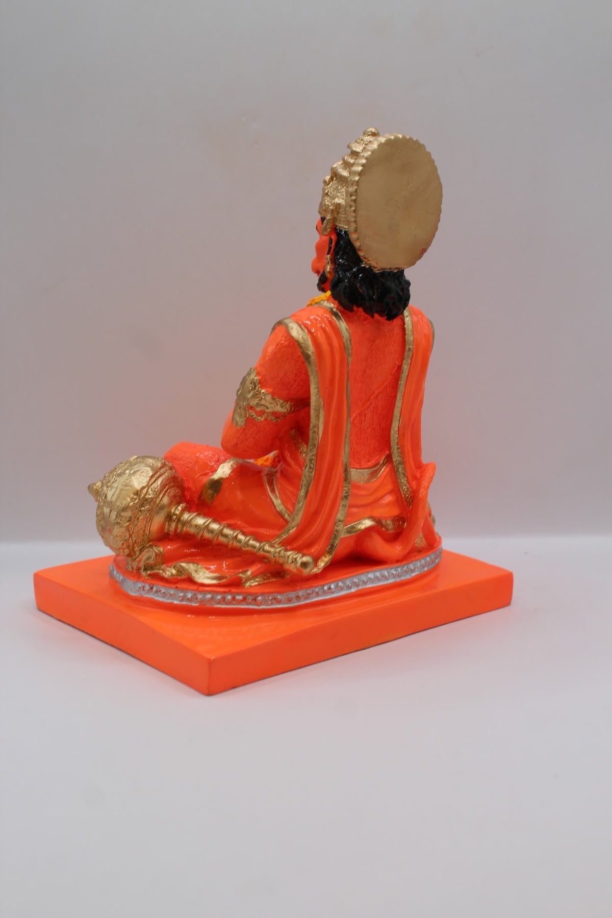 Orange resin Hanuman murti seated in prayer, back view