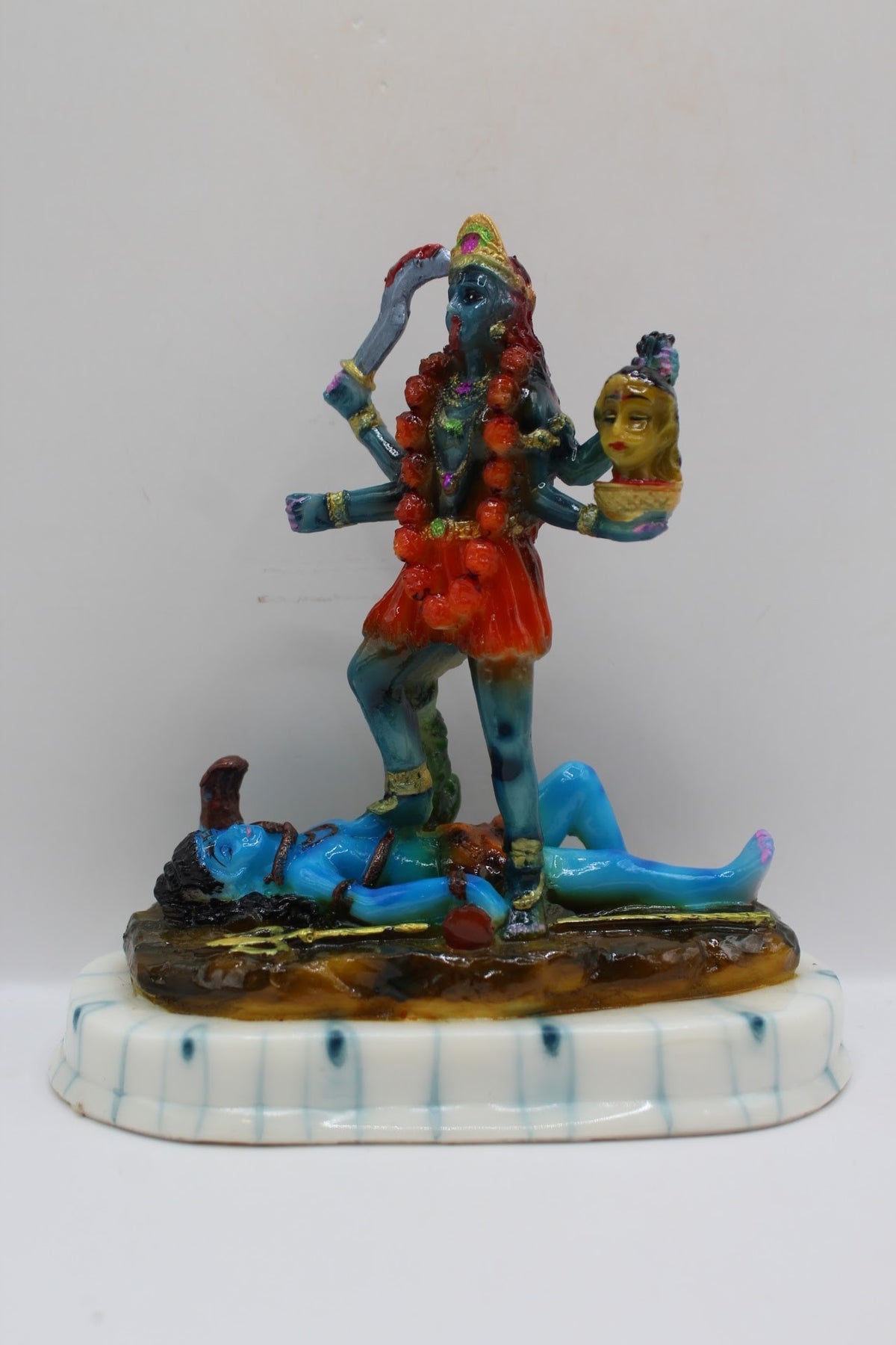 Blue resin Kali Mata murti on a white base, front view