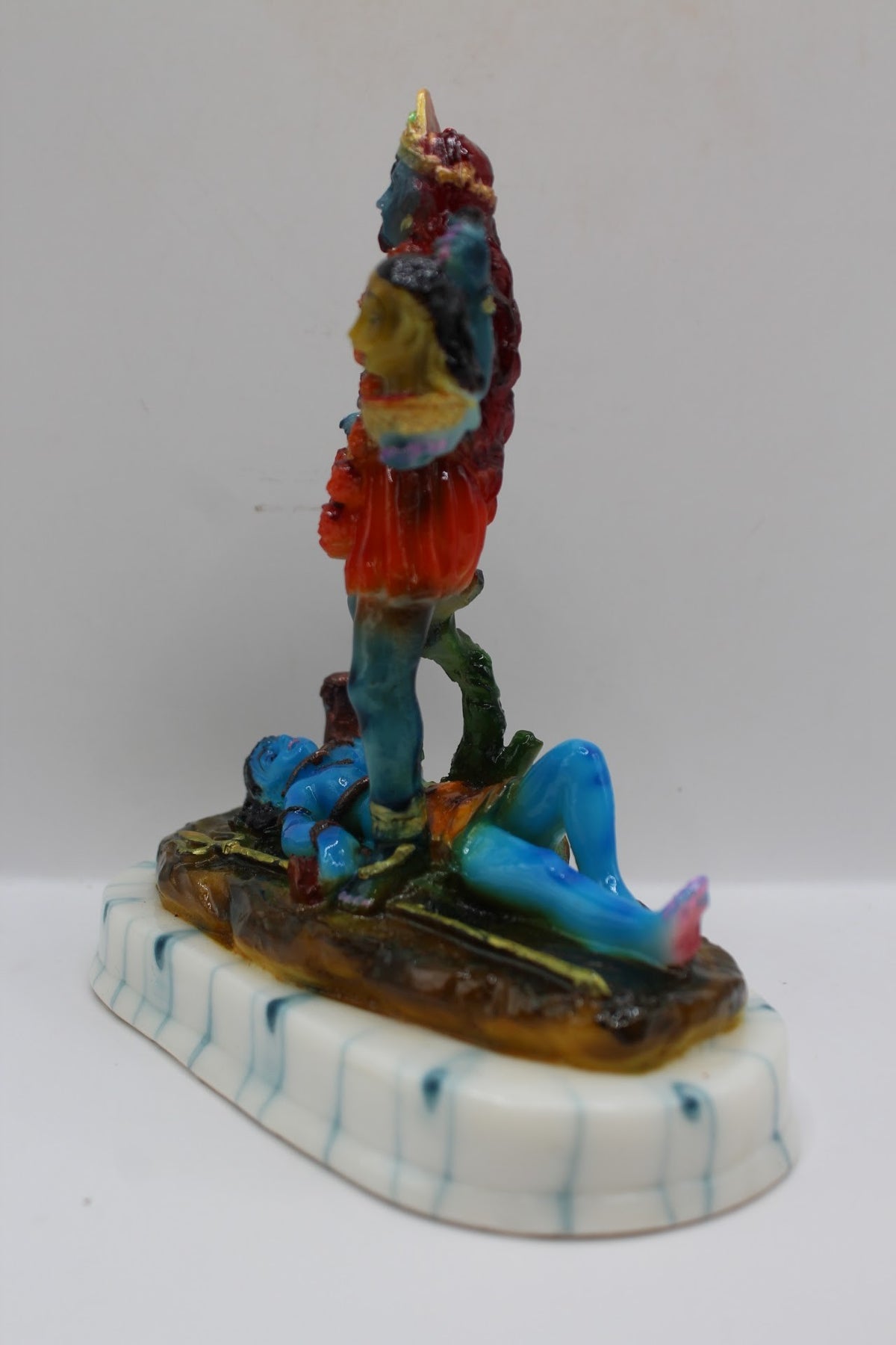 Blue resin Kali Mata murti on a white base, right side view
